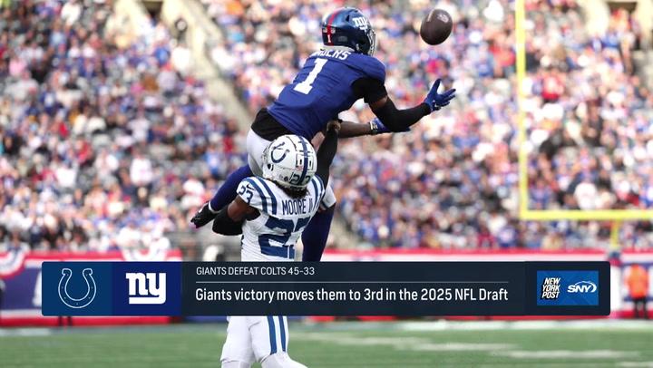 Giants player makes a leaping catch over Colts defender during NFL Week 16. Giants victory impacts 2025 draft position.