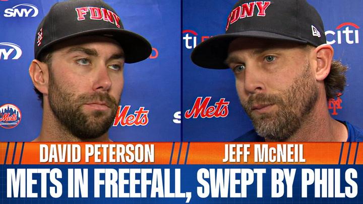 Two men in Mets caps react.