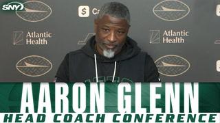 Aaron Glenn at Jets head coach conference with SNY and Atlantic Health logos in background.