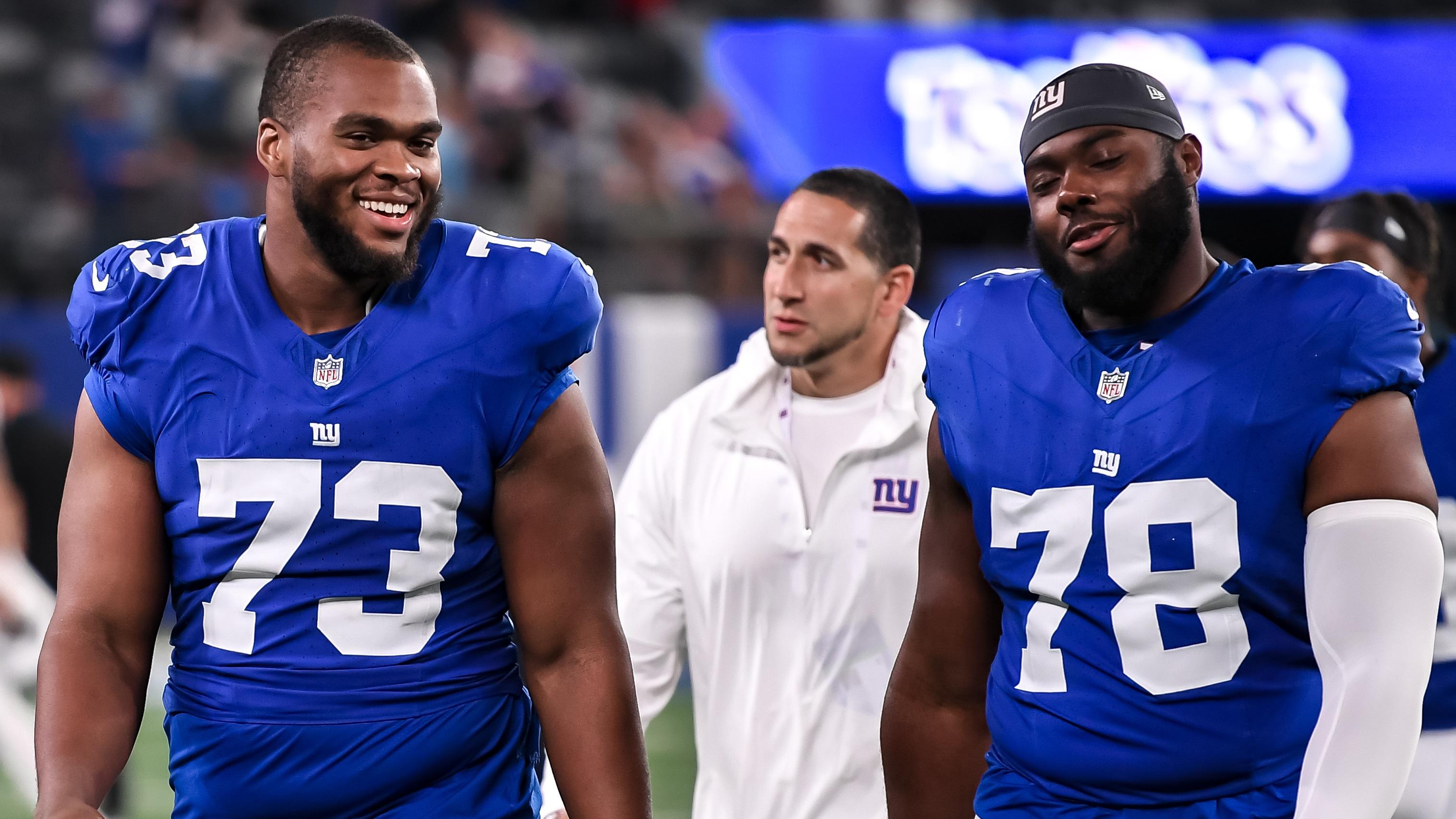 Giants offensive tackle Evan Neal (73) and New York Giants offensive tackle Andrew Thomas (78) exit the field after defeating the Carolina Panthers at MetLife Stadium