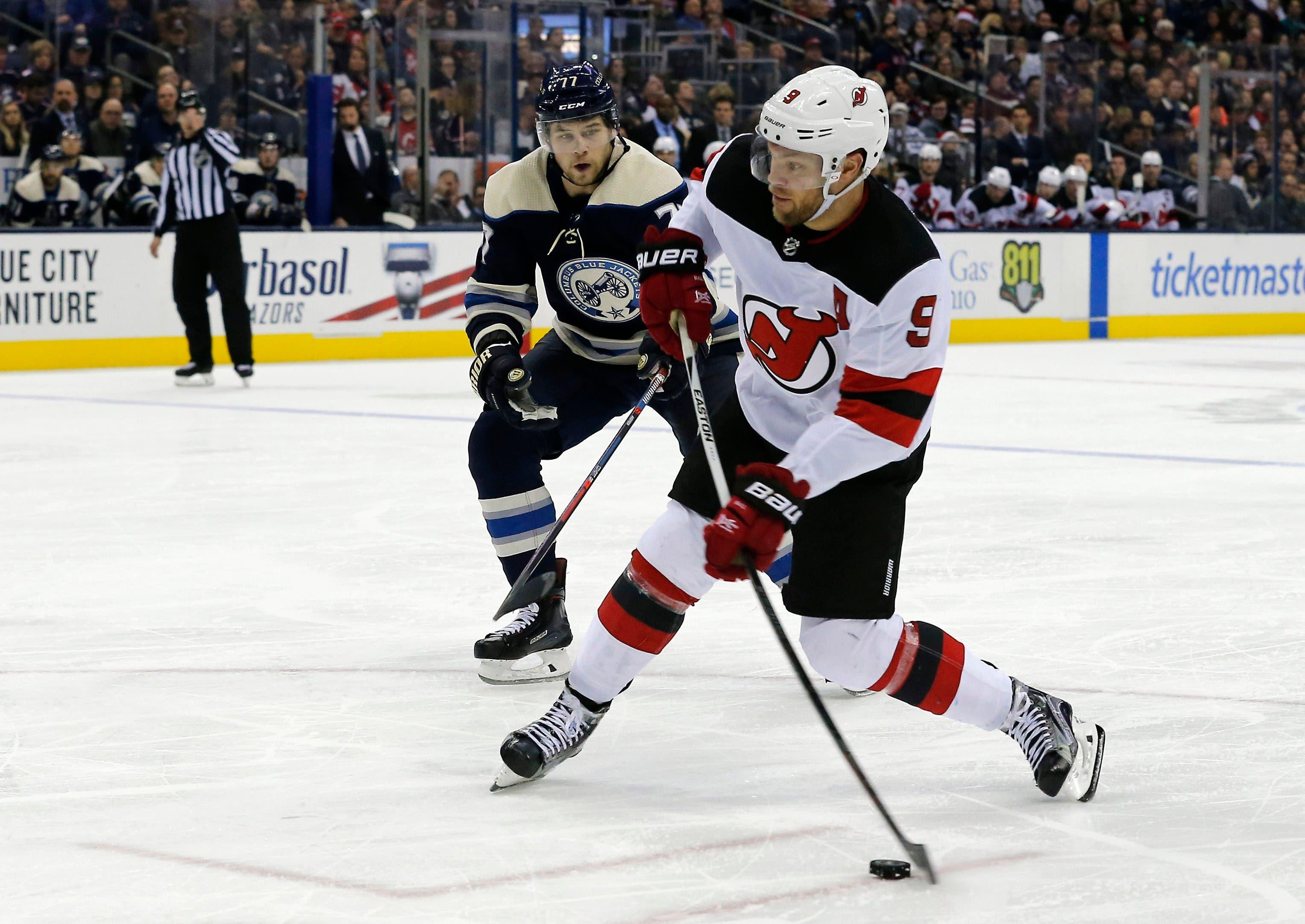 Dec 20, 2018; Columbus, OH, USA; New Jersey Devils left wing Taylor Hall (9) takes a shot as Columbus Blue Jackets right wing Josh Anderson (77) trails the play during the third period at Nationwide Arena. Mandatory Credit: Russell LaBounty-USA TODAY Sports / Russell LaBounty