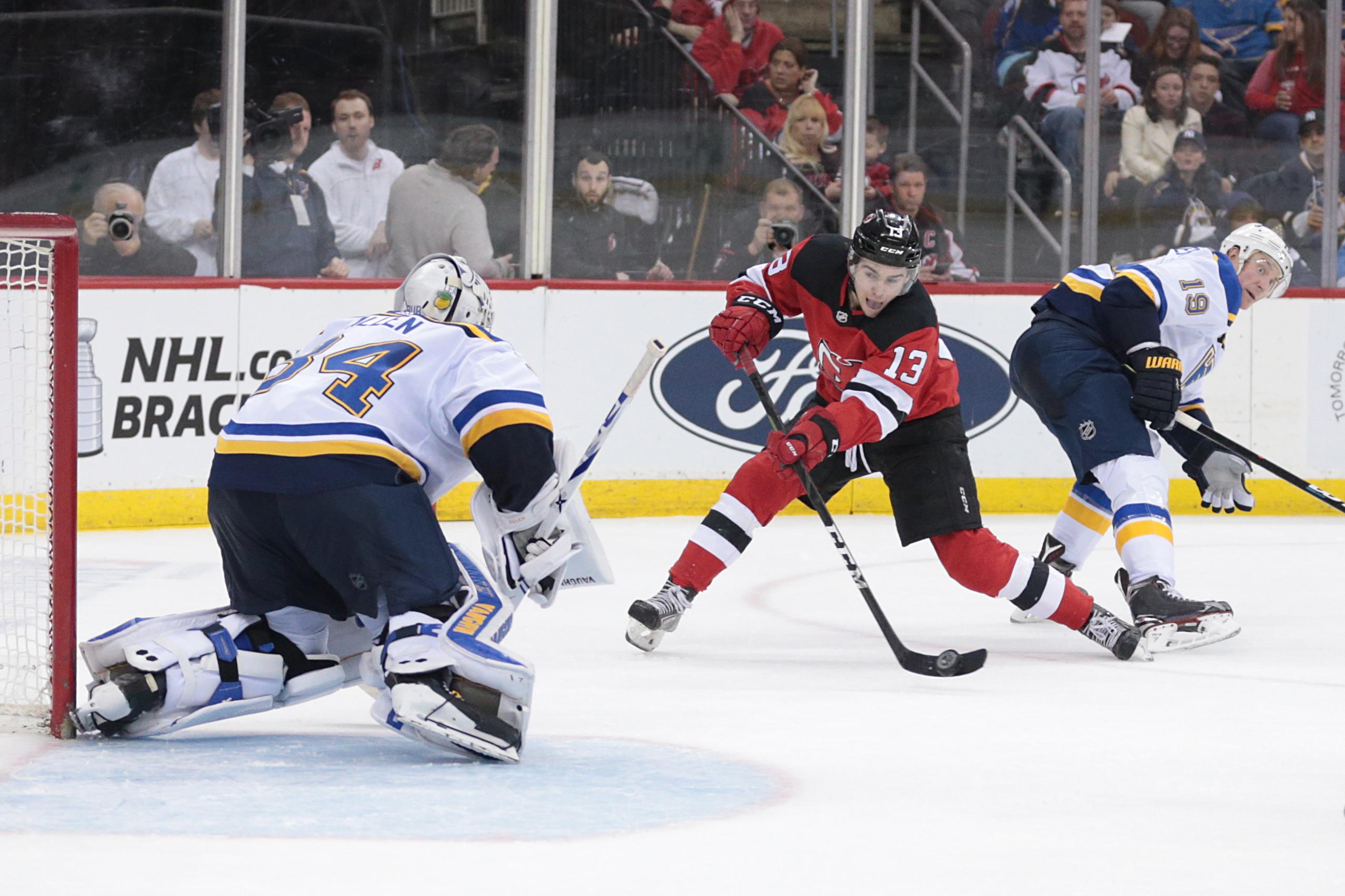 Mar 30, 2019; Newark, NJ, USA; New Jersey Devils center Nico Hischier (13) shoots the puck at St. Louis Blues goaltender Jake Allen (34) in front of defenseman Jay Bouwmeester (19) during the second period at Prudential Center. Mandatory Credit: Vincent Carchietta-USA TODAY Sports