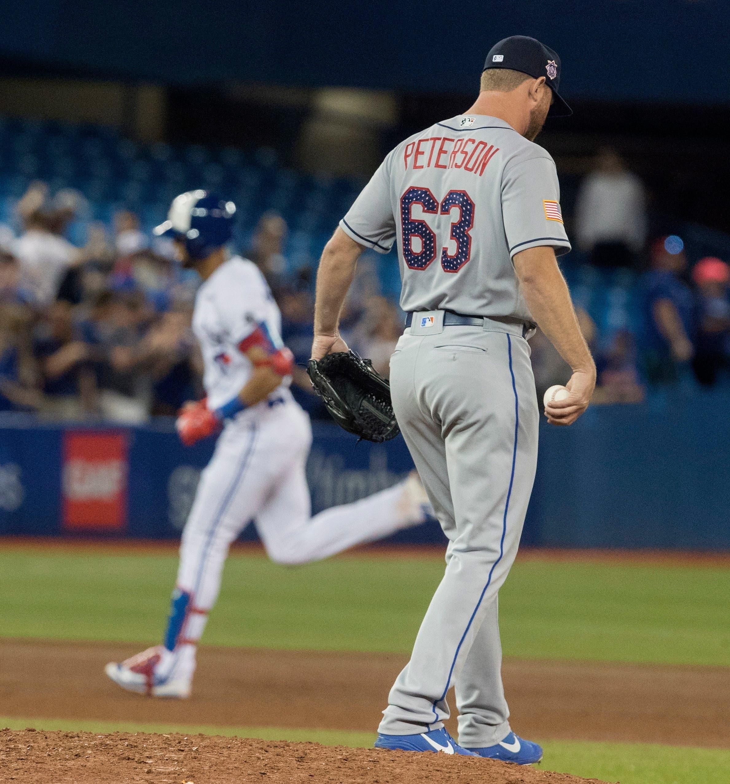 New York Mets pitcher Tim Peterson walks off the mound after giving up a two-run home run as Toronto Blue Jays' Lourdes Gurriel Jr. rounds the bases. / AP