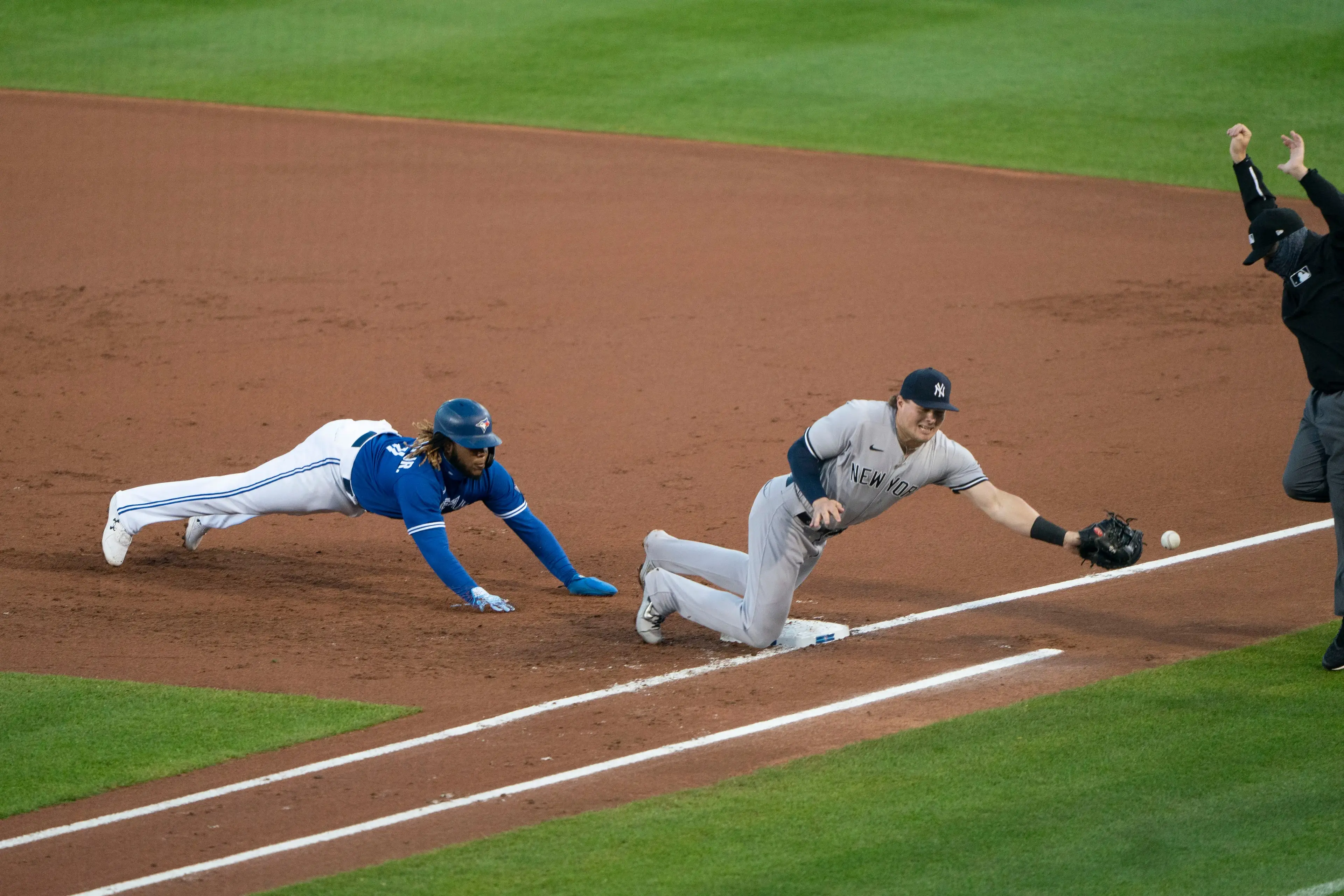 Sep 23, 2020; Buffalo, New York, USA; New York Yankees catcher Gary Sanchez (24) (not pictured) throws the ball wide of New York Yankees first baseman Luke Voit (59) with Toronto Blue Jays first baseman Vladimir Guerrero Jr. (27) diving back to the base during the first inning at Sahlen Field. Mandatory Credit: Gregory Fisher-USA TODAY Sports / © Gregory Fisher-USA TODAY Sports