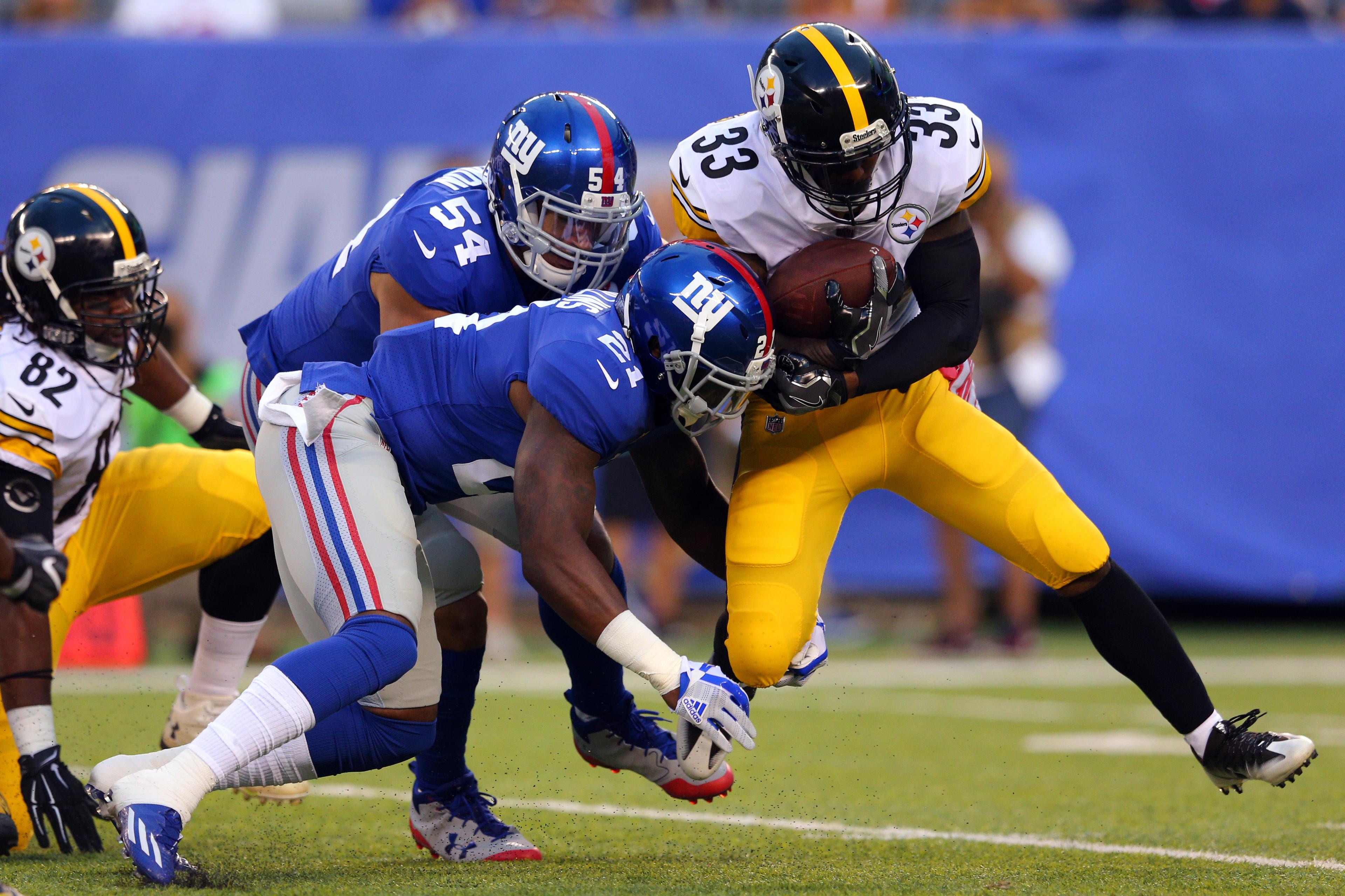 Pittsburgh Steelers running back Fitzgerald Toussaint is tackled by New York Giants defensive end Olivier Vernon and safety Landon Collins during the first quarter of a preseason game at MetLife Stadium.