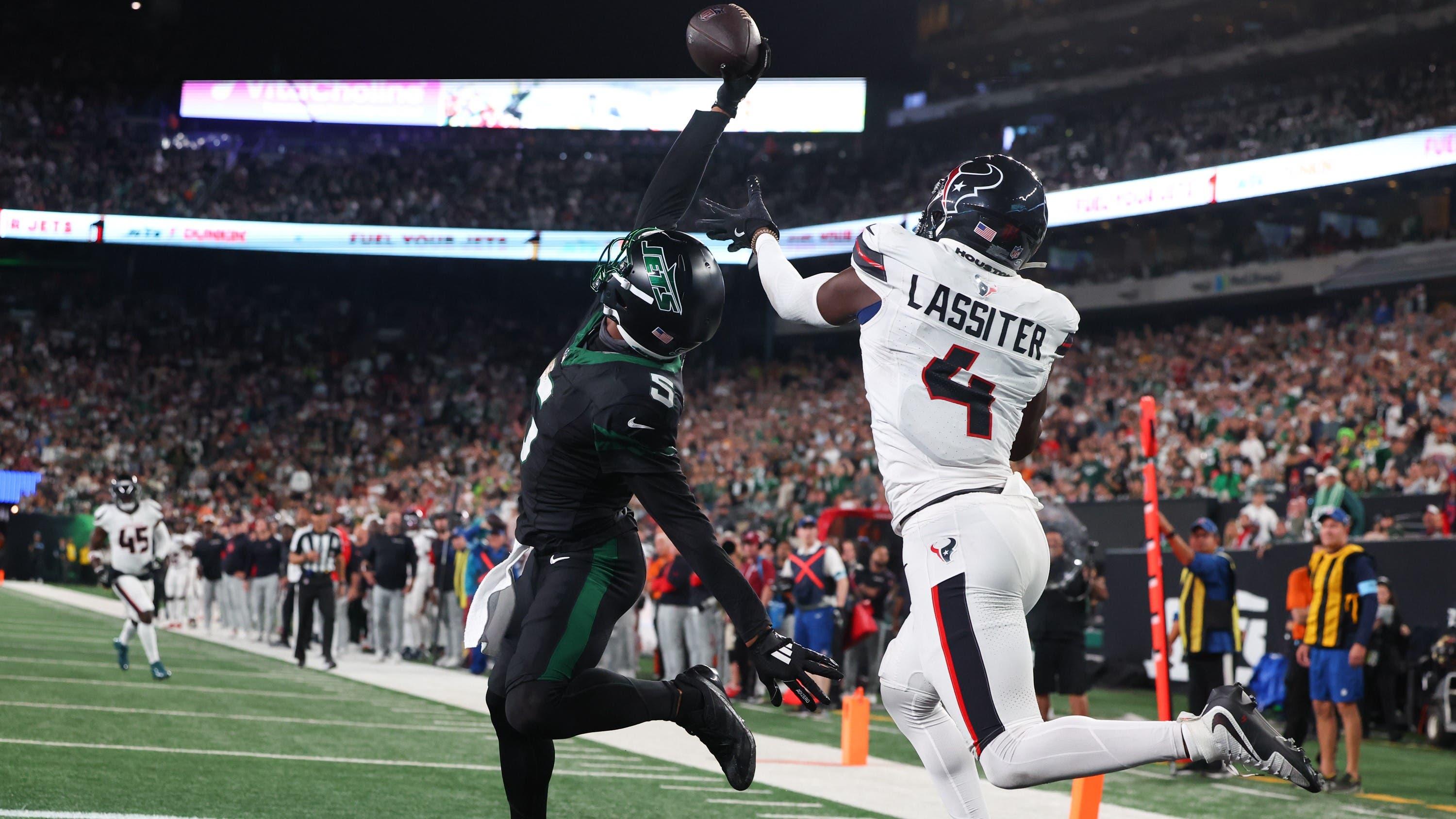 Oct 31, 2024; East Rutherford, New Jersey, USA; New York Jets wide receiver Garrett Wilson (5) catches a touchdown pass while being defended by Houston Texans cornerback Kamari Lassiter (4) during the second half at MetLife Stadium. Mandatory Credit: Ed Mulholland-Imagn Images