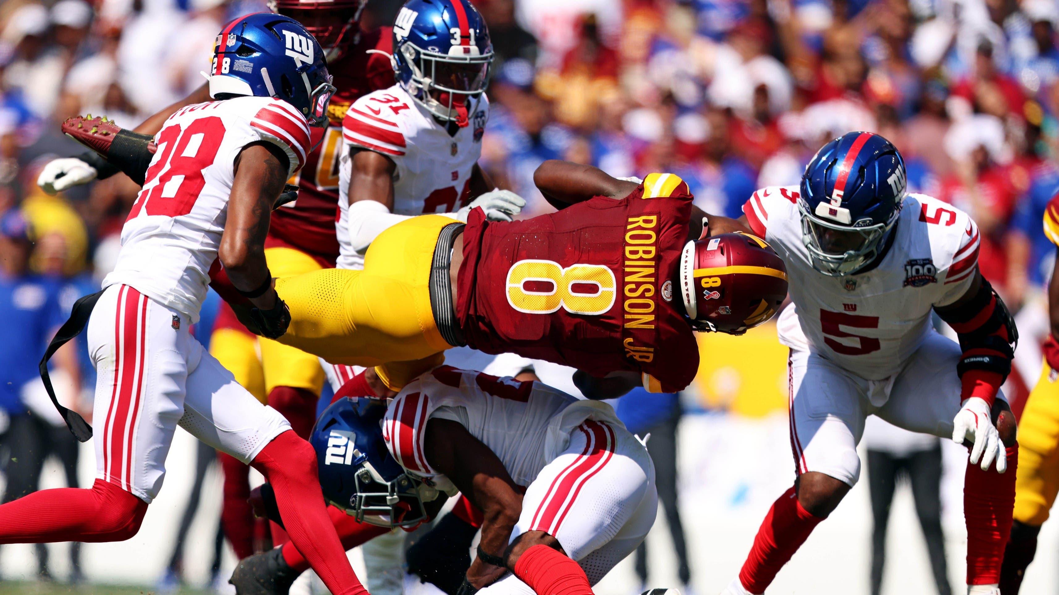 Sep 15, 2024; Landover, Maryland, USA; Washington Commanders running back Brian Robinson Jr. (8) is tackled by New York Giants cornerback Dru Phillips (22) during the second quarter at Commanders Field. / Peter Casey-Imagn Images