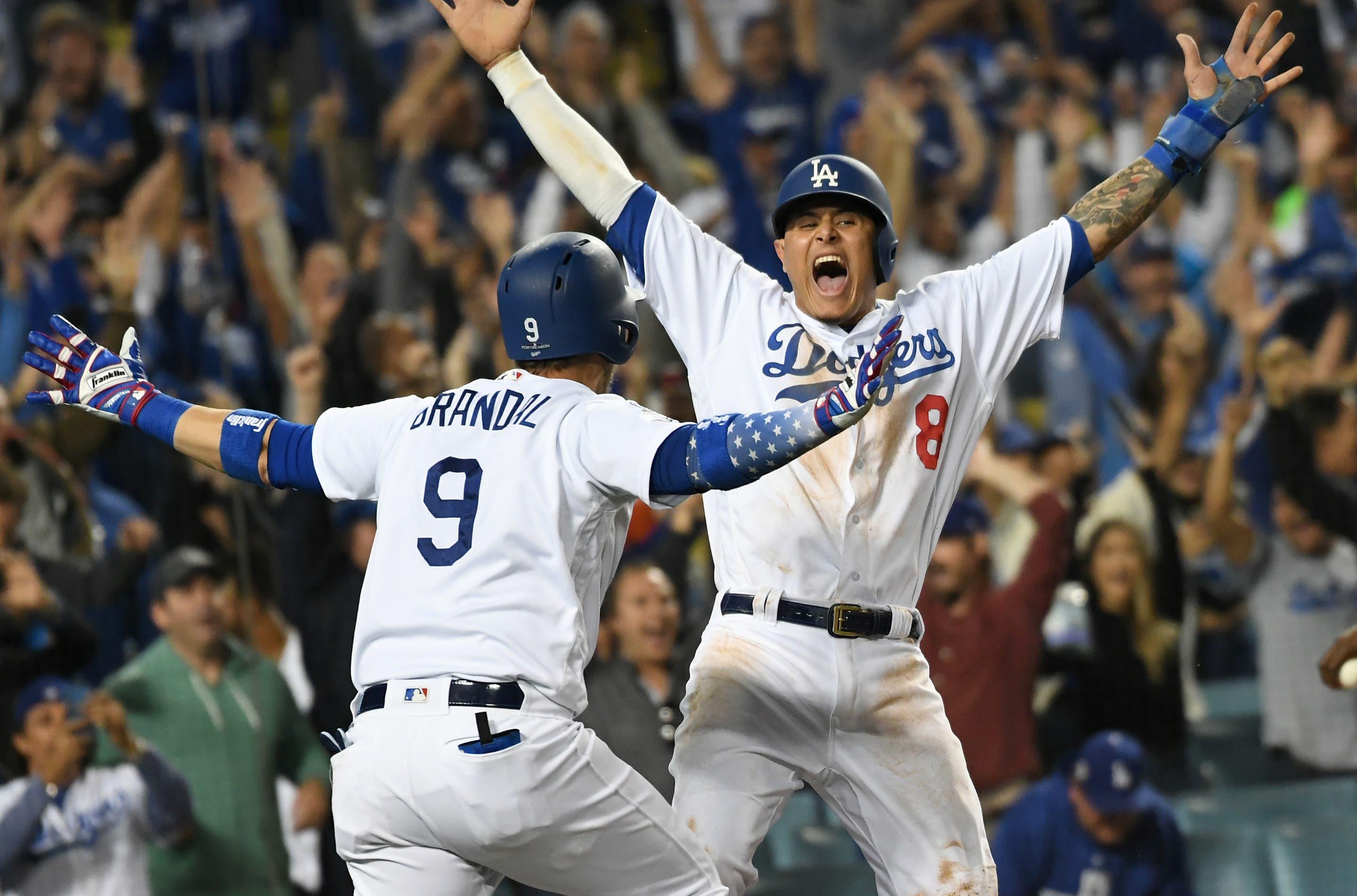 Oct 16, 2018; Los Angeles, CA, USA; Los Angeles Dodgers shortstop Manny Machado (8) celebrates with catcher Yasmani Grandal (9) after scoring on an RBI single by center fielder Cody Bellinger (not pictured) defeat the Milwaukee Brewers in the thirteenth inning in game four of the 2018 NLCS playoff baseball series at Dodger Stadium. Mandatory Credit: Richard Mackson-USA TODAY Sports / Richard Mackson