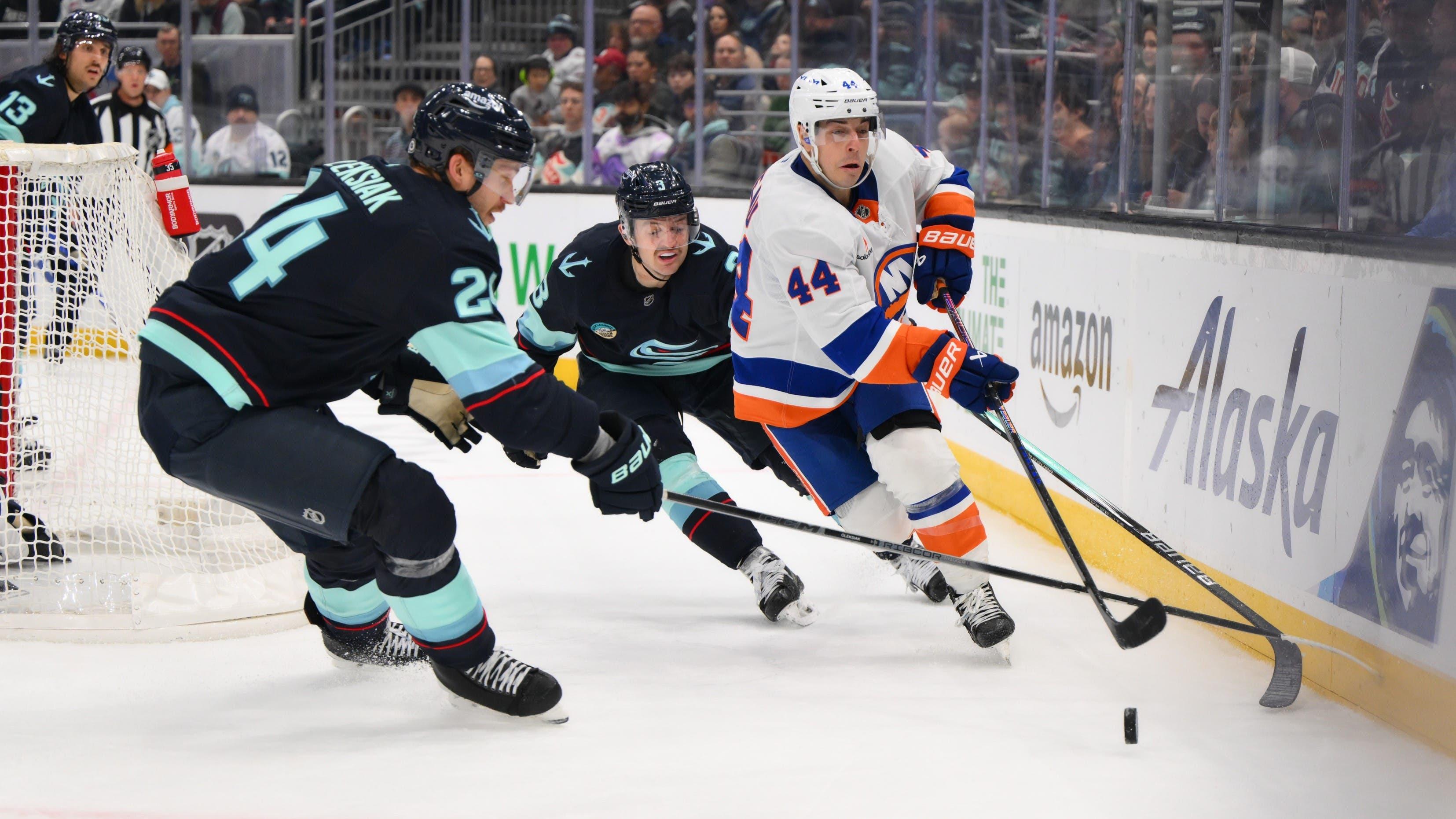 Nov 16, 2024; Seattle, Washington, USA; New York Islanders center Jean-Gabriel Pageau (44) plays the puck while defended by Seattle Kraken defenseman Jamie Oleksiak (24) and defenseman Will Borgen (3) during the second period at Climate Pledge Arena. / Steven Bisig-Imagn Images