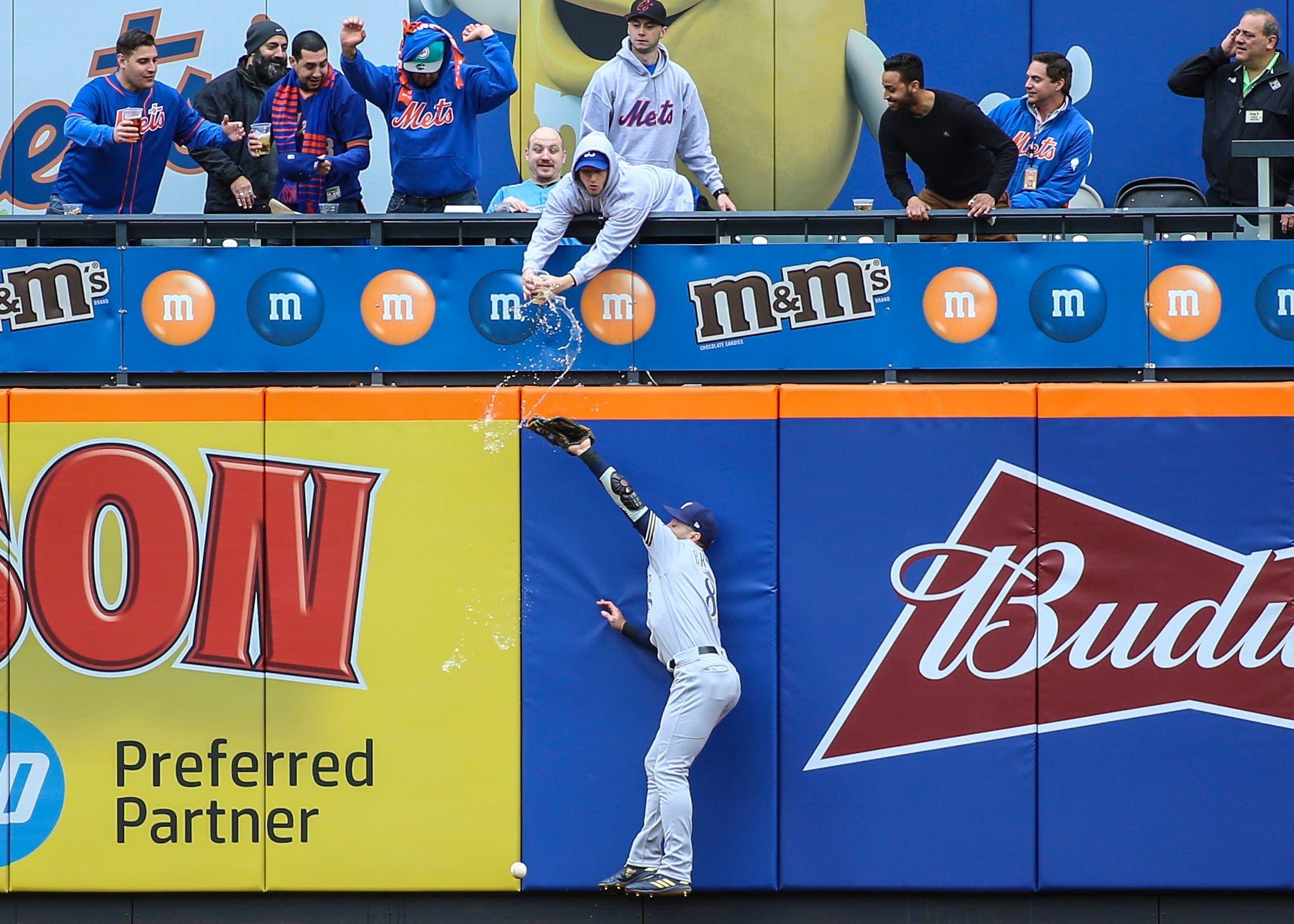 Milwaukee Brewers left fielder Ryan Braun and a fan in the stands try to catch the ball in the first inning against the New York Mets at Citi Field. / Wendell Cruz/USA TODAY Sports