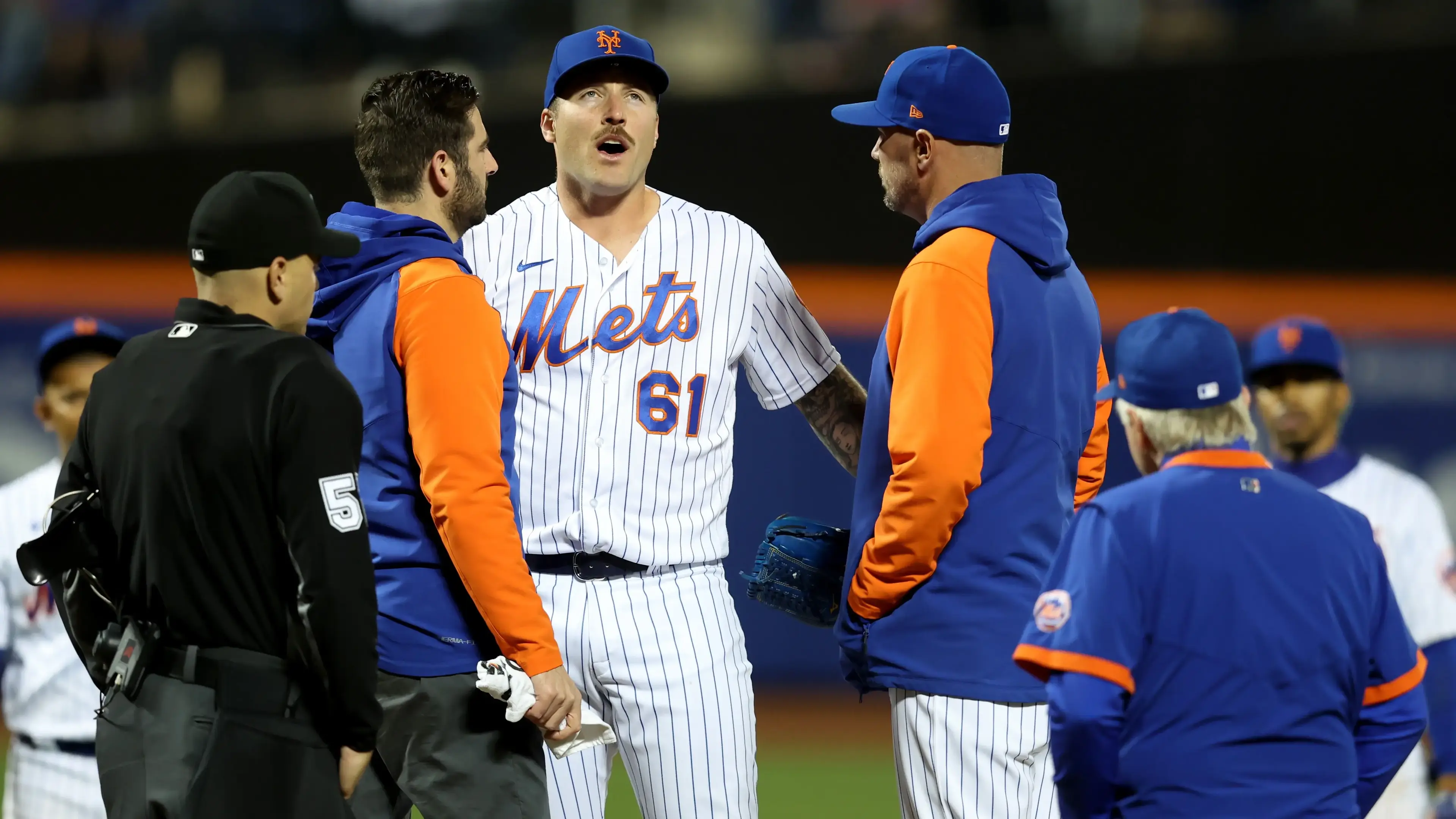 New York Mets relief pitcher Sean Reid-Foley (61) talks to coaches and trainers and home plate umpire Jansen Visconti (52) before leaving the game with an apparent injury during the eighth inning / Brad Penner-USA TODAY Sports
