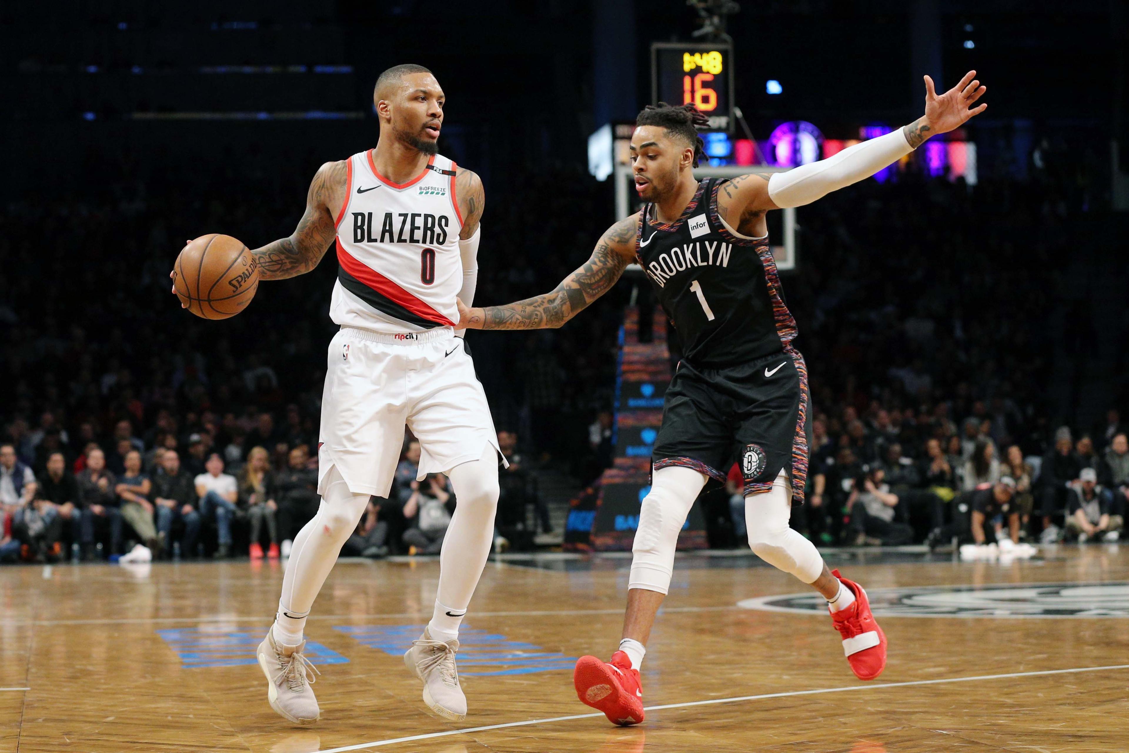 Feb 21, 2019; Brooklyn, NY, USA; Portland Trail Blazers point guard Damian Lillard (0) plays the ball against Brooklyn Nets point guard D'Angelo Russell (1) during the fourth quarter at Barclays Center. Mandatory Credit: Brad Penner-USA TODAY Sports / Brad Penner