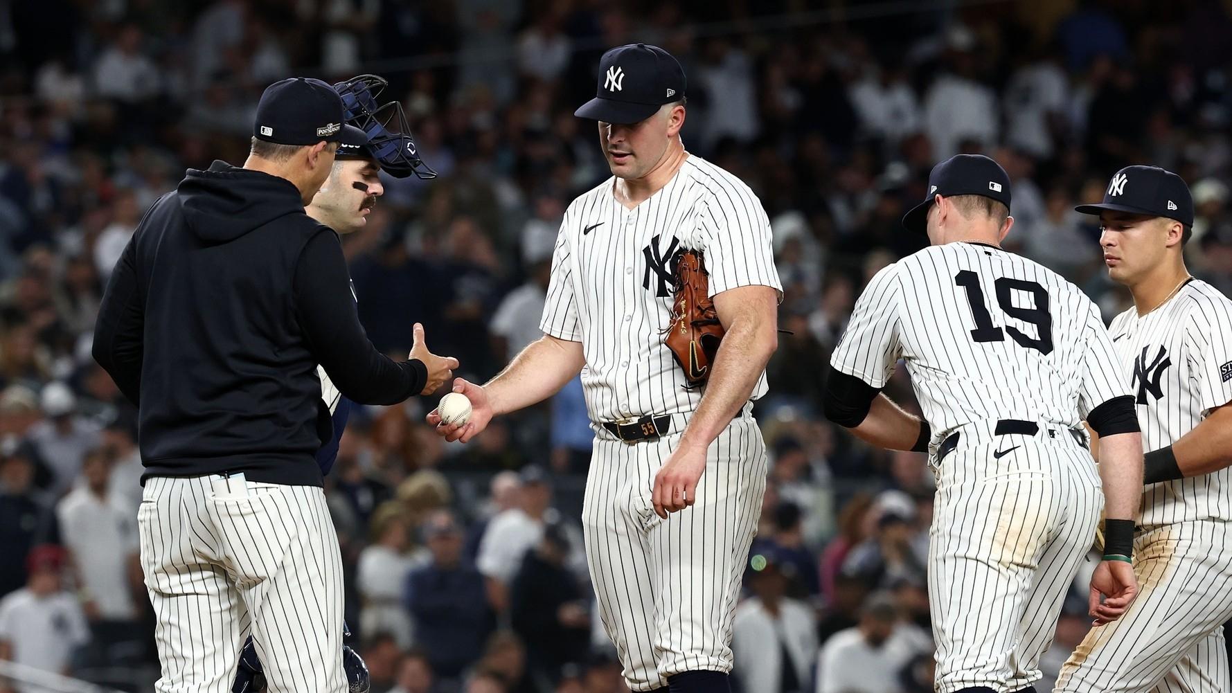 New York Yankees pitcher Carlos Rodon (55) hands the ball to manager Aaron Boone (17) in the fourth inning during game two of the ALDS for the 2024 MLB Playoffs at Yankee Stadium.