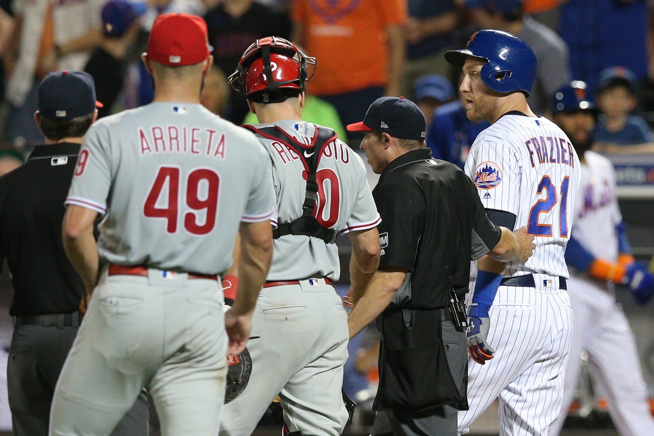 Jul 6, 2019; New York City, NY, USA; New York Mets third baseman Todd Frazier (21) is escorted to first base by home plate umpire Tripp Gibson (73) and Philadelphia Phillies catcher J.T. Realmuto (10) after being hit by a pitch by Phillies starting pitcher Jake Arrieta (49) during the fifth inning at Citi Field. Mandatory Credit: Brad Penner-USA TODAY Sports / Brad Penner