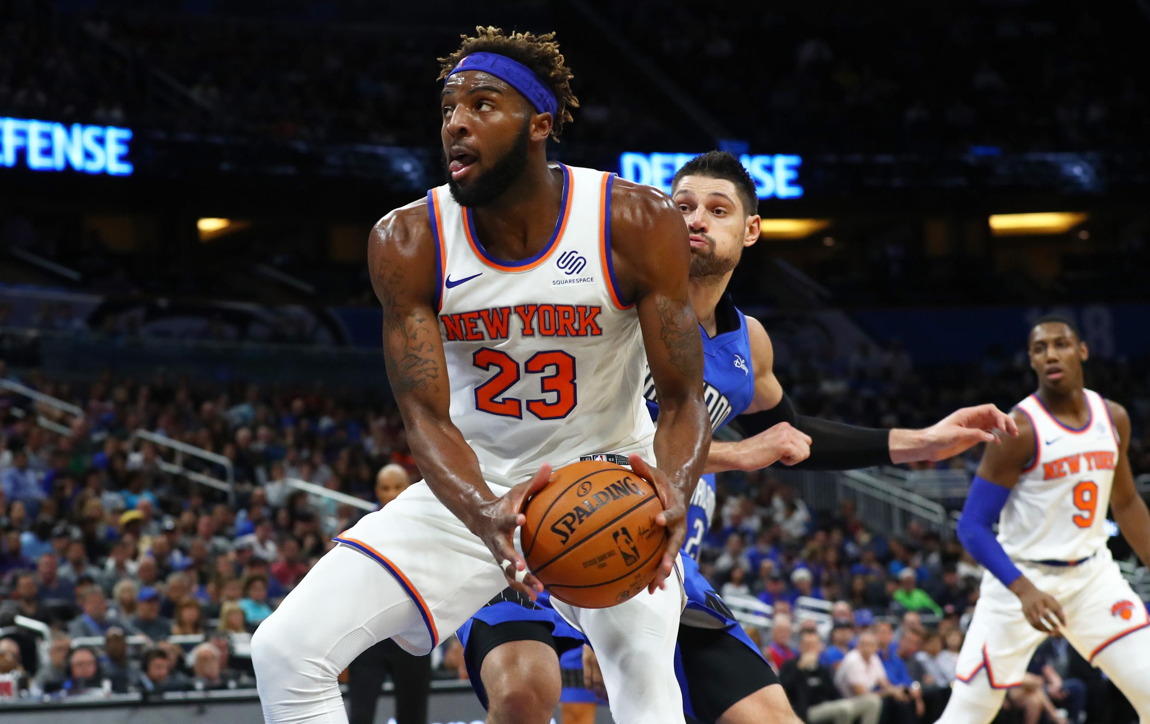 Oct 30, 2019; Orlando, FL, USA; New York Knicks center Mitchell Robinson (23) drives past Orlando Magic center Nikola Vucevic (9) and shoots a layup during the second quarter at Amway Center. Mandatory Credit: Kim Klement-USA TODAY Sports / Kim Klement