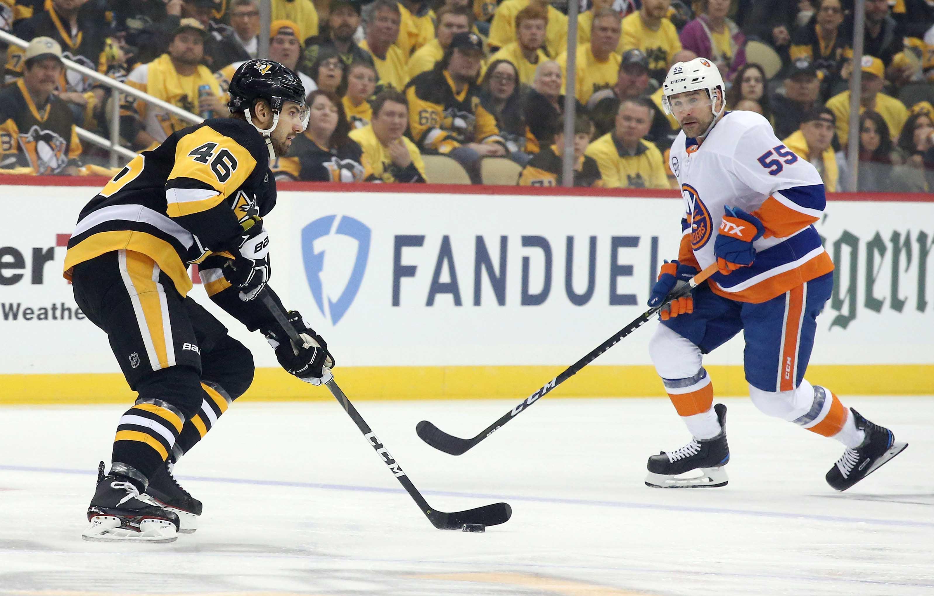 Pittsburgh Penguins center Zach Aston-Reese moves the puck as New York Islanders defenseman Johnny Boychuk defends during the first period in Game 3 of the first round of the 2019 Stanley Cup Playoffs at PPG PAINTS Arena.