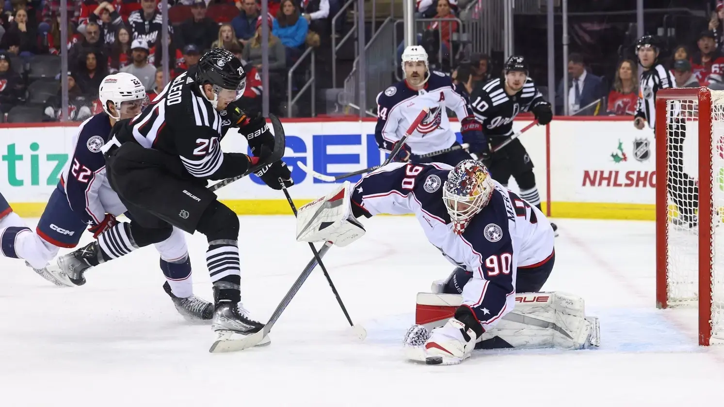 Columbus Blue Jackets goaltender Elvis Merzlikins (90) makes a save while New Jersey Devils center Michael McLeod (20) looks for the rebound during the second period at Prudential Center. / Ed Mulholland-USA TODAY Sports