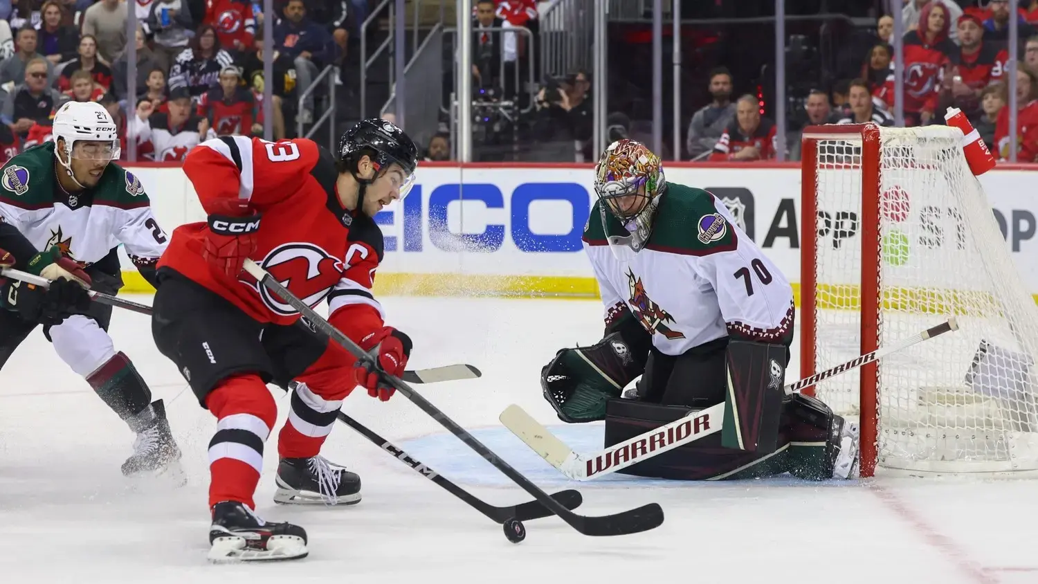 Oct 13, 2023; Newark, New Jersey, USA; Arizona Coyotes goaltender Karel Vejmelka (70) defends his net against New Jersey Devils center Nico Hischier (13) during the second period at Prudential Center. / Ed Mulholland-USA TODAY Sports