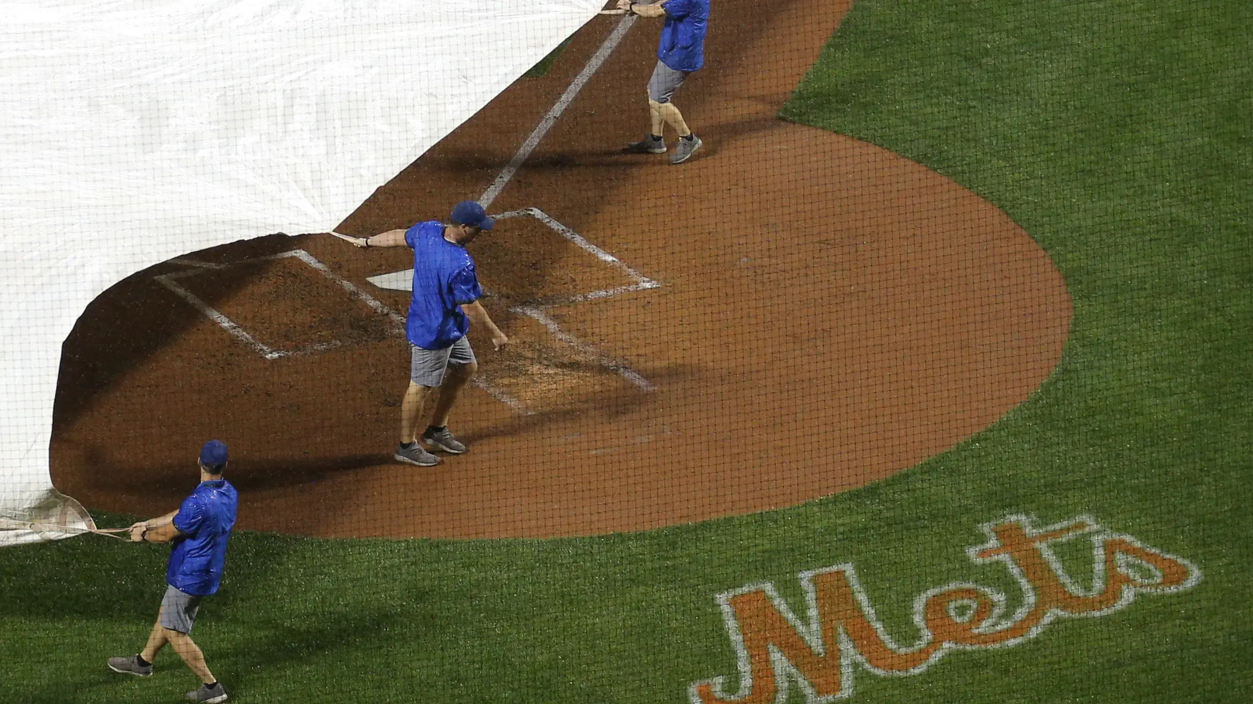 Aug 10, 2021; New York City, New York, USA; Members of the grounds crew roll the tarp onto the infield during a thunderstorm in the second inning of a game between the New York Mets and the Washington Nationals at Citi Field. / Brad Penner-USA TODAY Sports