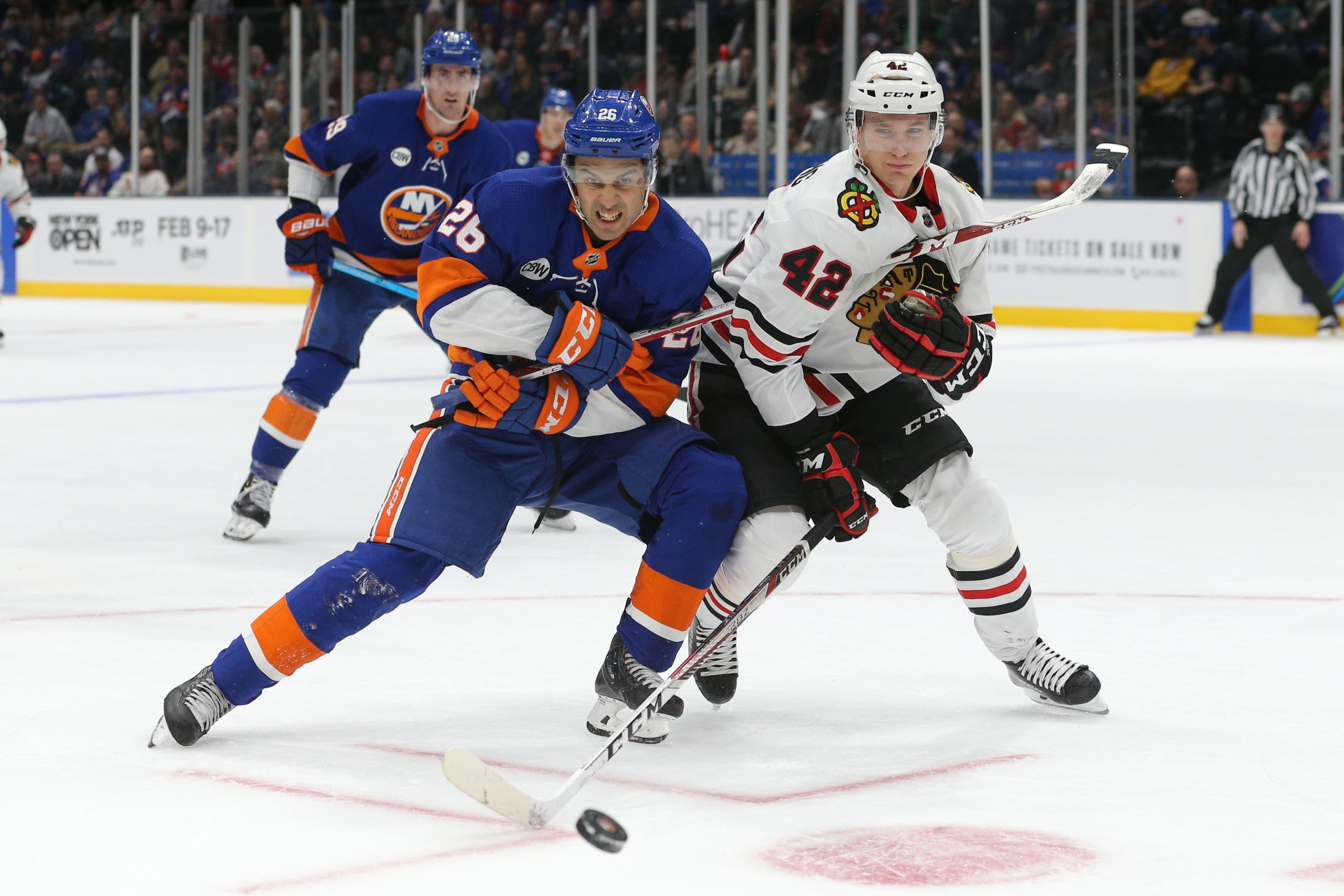 Jan 3, 2019; Uniondale, NY, USA; New York Islanders right wing Josh Ho-Sang (26) and Chicago Blackhawks defenseman Gustav Forsling (42) fight for a loose puck during the second period at Nassau Veterans Memorial Coliseum. Mandatory Credit: Brad Penner-USA TODAY Sports / Brad Penner