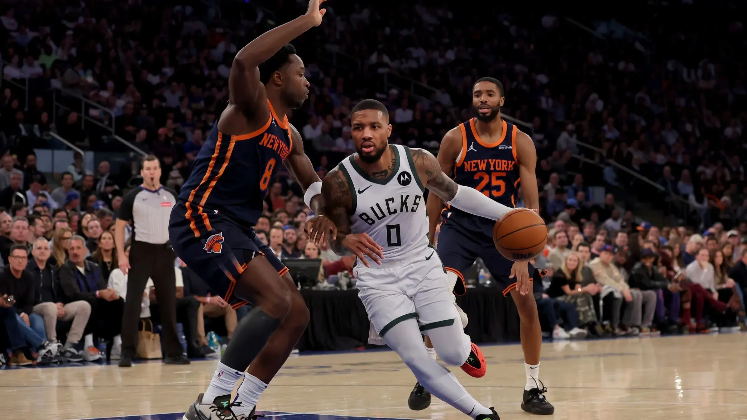 Nov 8, 2024; New York, New York, USA; Milwaukee Bucks guard Damian Lillard (0) drives to the basket against New York Knicks forwards OG Anunoby (8) and Mikal Bridges (25) during the second quarter at Madison Square Garden. / Brad Penner-Imagn Images