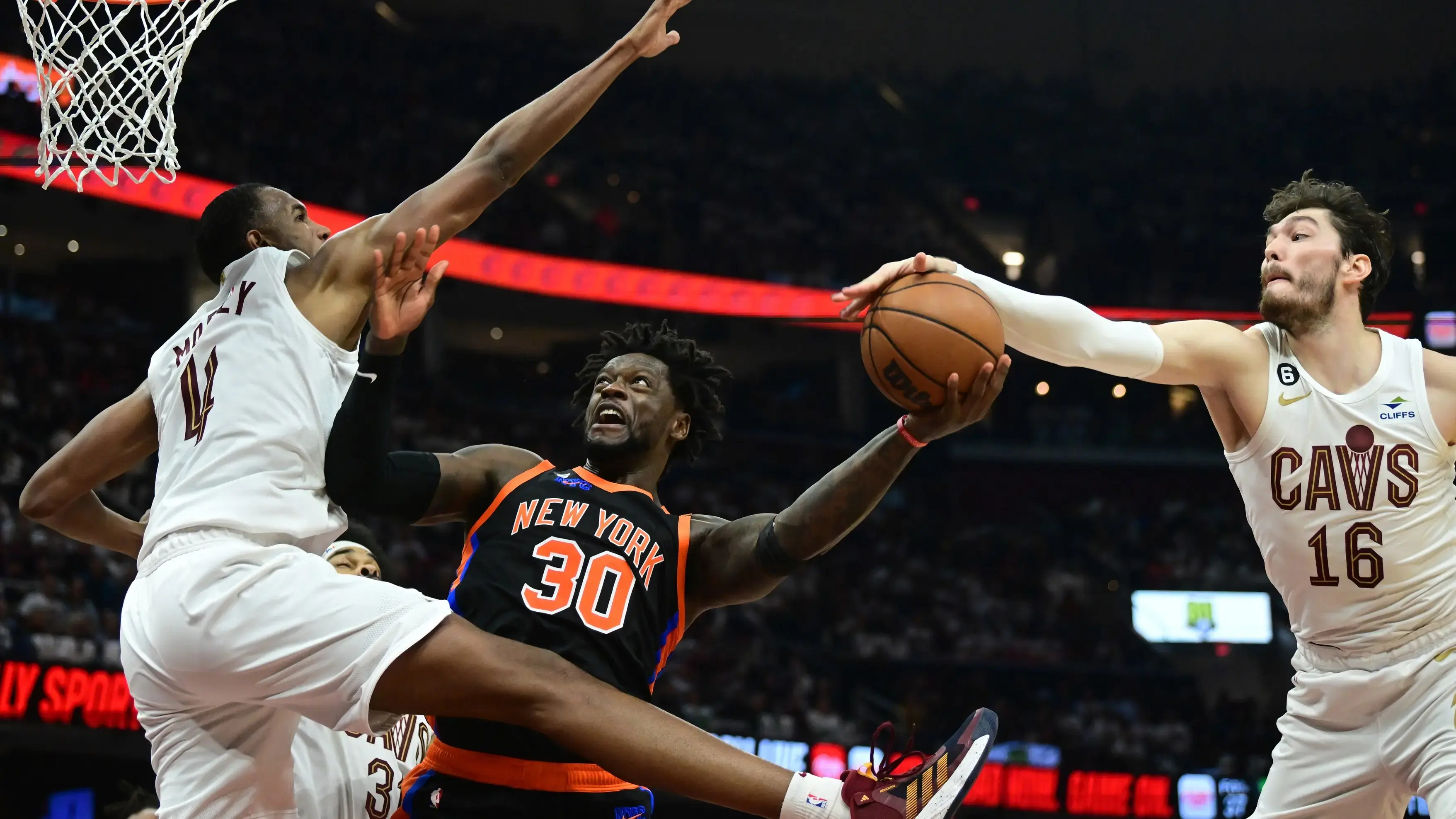 Apr 18, 2023; Cleveland, Ohio, USA; New York Knicks forward Julius Randle (30) drives to the basket between Cleveland Cavaliers forward Evan Mobley (4) and forward Cedi Osman (16) during the second quarter of game two of the 2023 NBA playoffs at Rocket Mortgage FieldHouse. / Ken Blaze-USA TODAY Sports