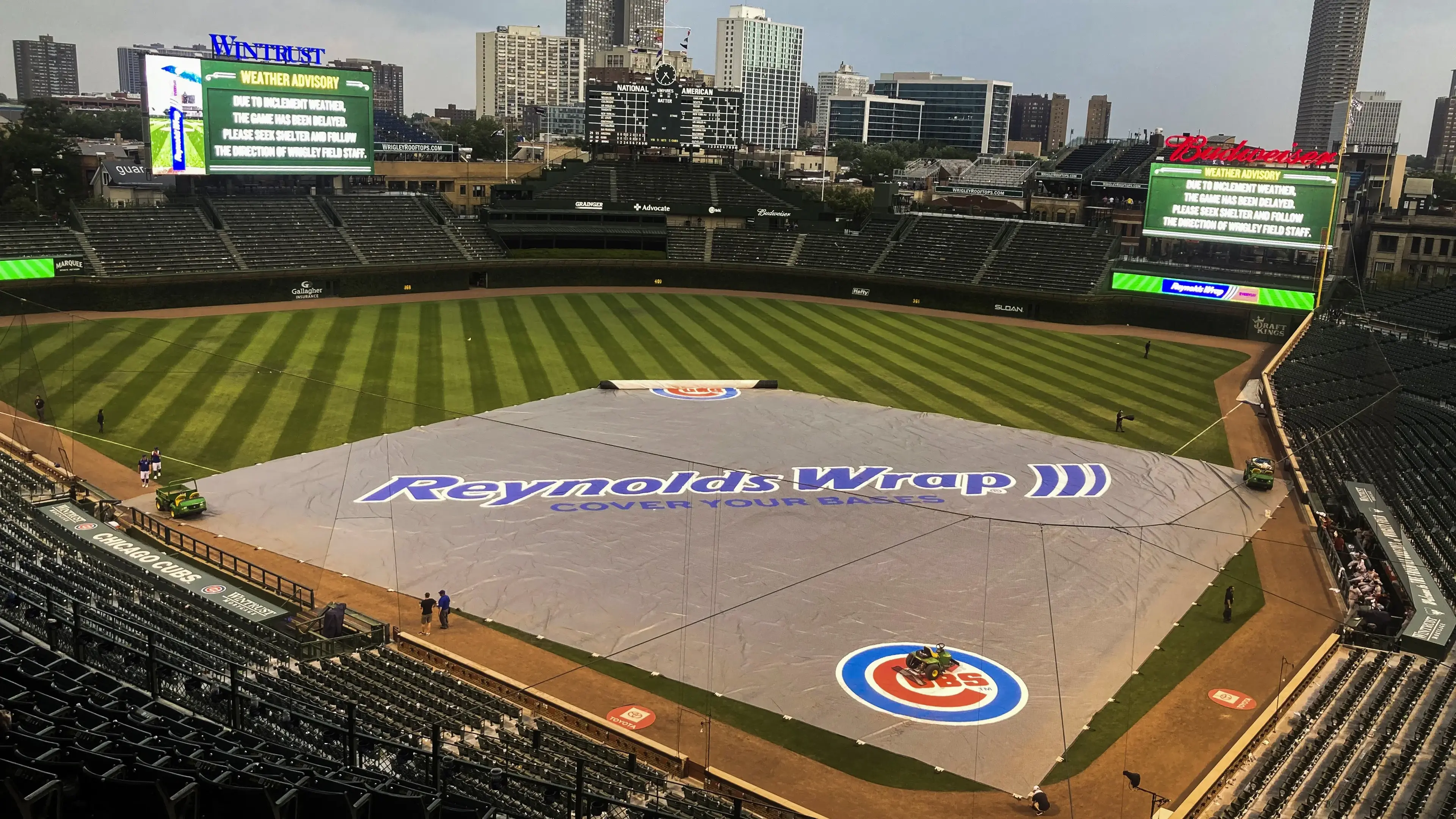 Jul 24, 2021; Chicago, Illinois, USA; Chicago Cubs grounds crew members place the tarp during a rain delay in the ninth inning against the Arizona Diamondbacks at Wrigley Field. Mandatory Credit: Matt Marton-USA TODAY Sports / Matt Marton-USA TODAY Sports