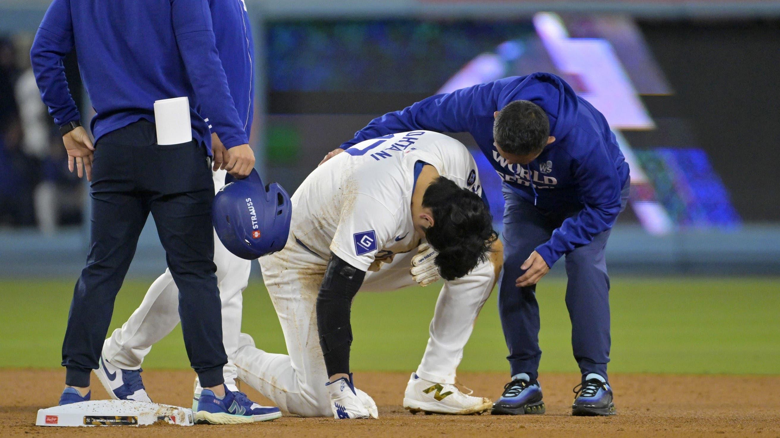 Oct 26, 2024; Los Angeles, California, USA; Los Angeles Dodgers manager Dave Roberts (30) and staff attend to designated hitter Shohei Ohtani (17) at second base after an apparent injury in the seventh inning against the New York Yankees during game two of the 2024 MLB World Series at Dodger Stadium.