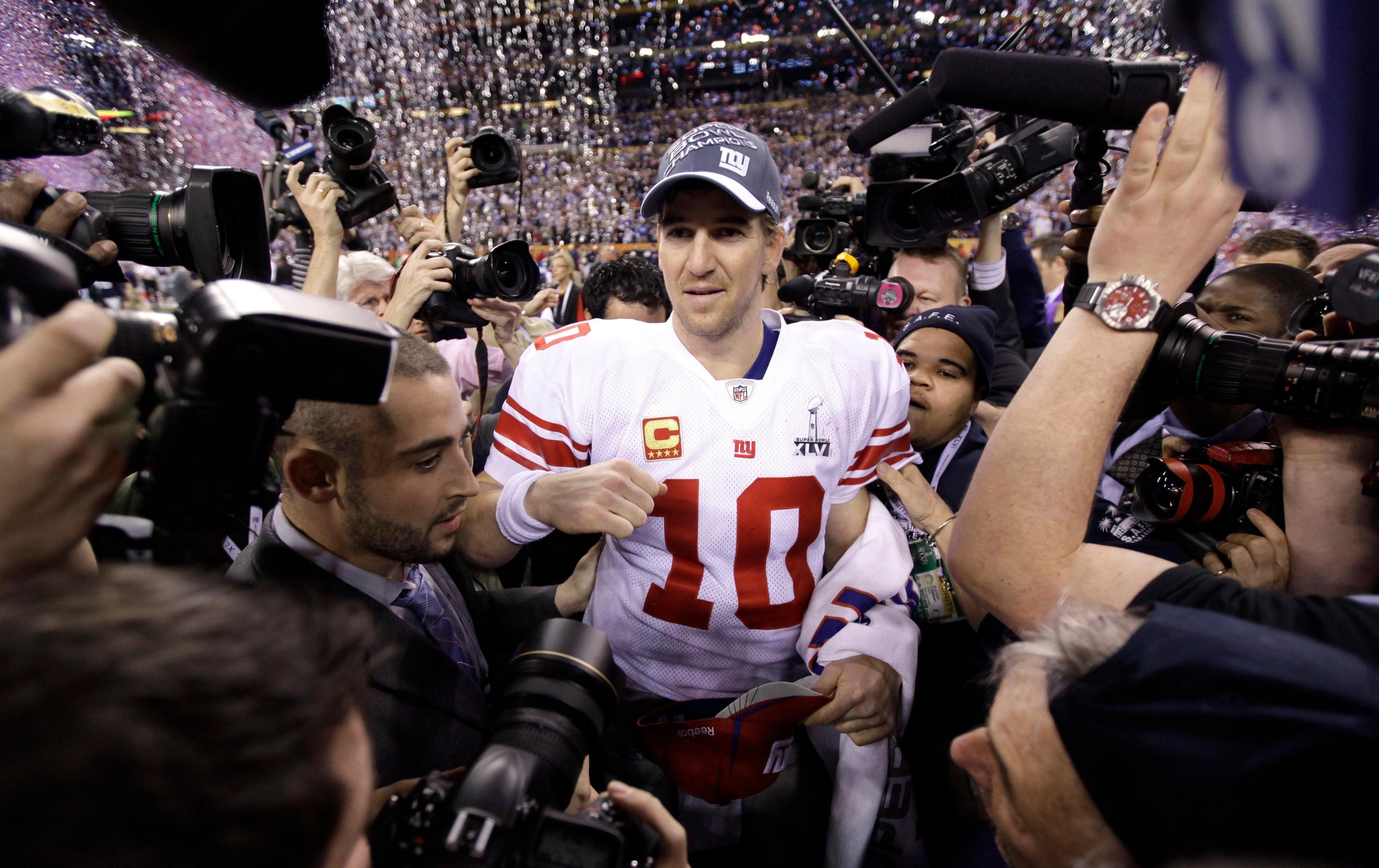 New York Giants quarterback Eli Manning, center, is surrounded by photographers as he celebrates his team's 21-17 win against New England Patriots after the NFL Super Bowl XLVI football game Sunday, Feb. 5, 2012, in Indianapolis. (AP Photo/Marcio Jose Sanchez) / Marcio Jose Sanchez/AP