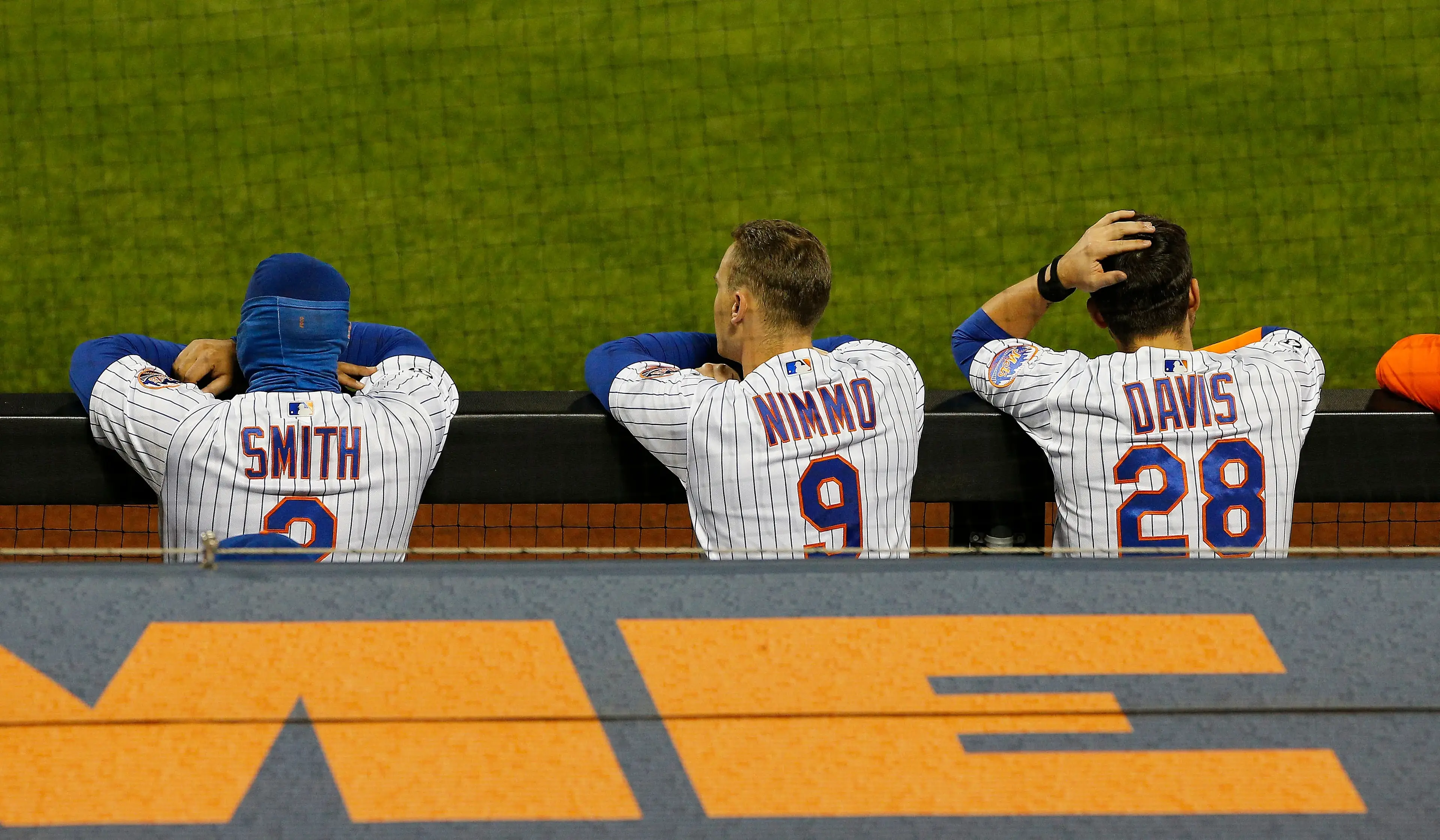 Dominic Smith, J.D. Davis, and Brandon Nimmo look on from the dugout / USA Today