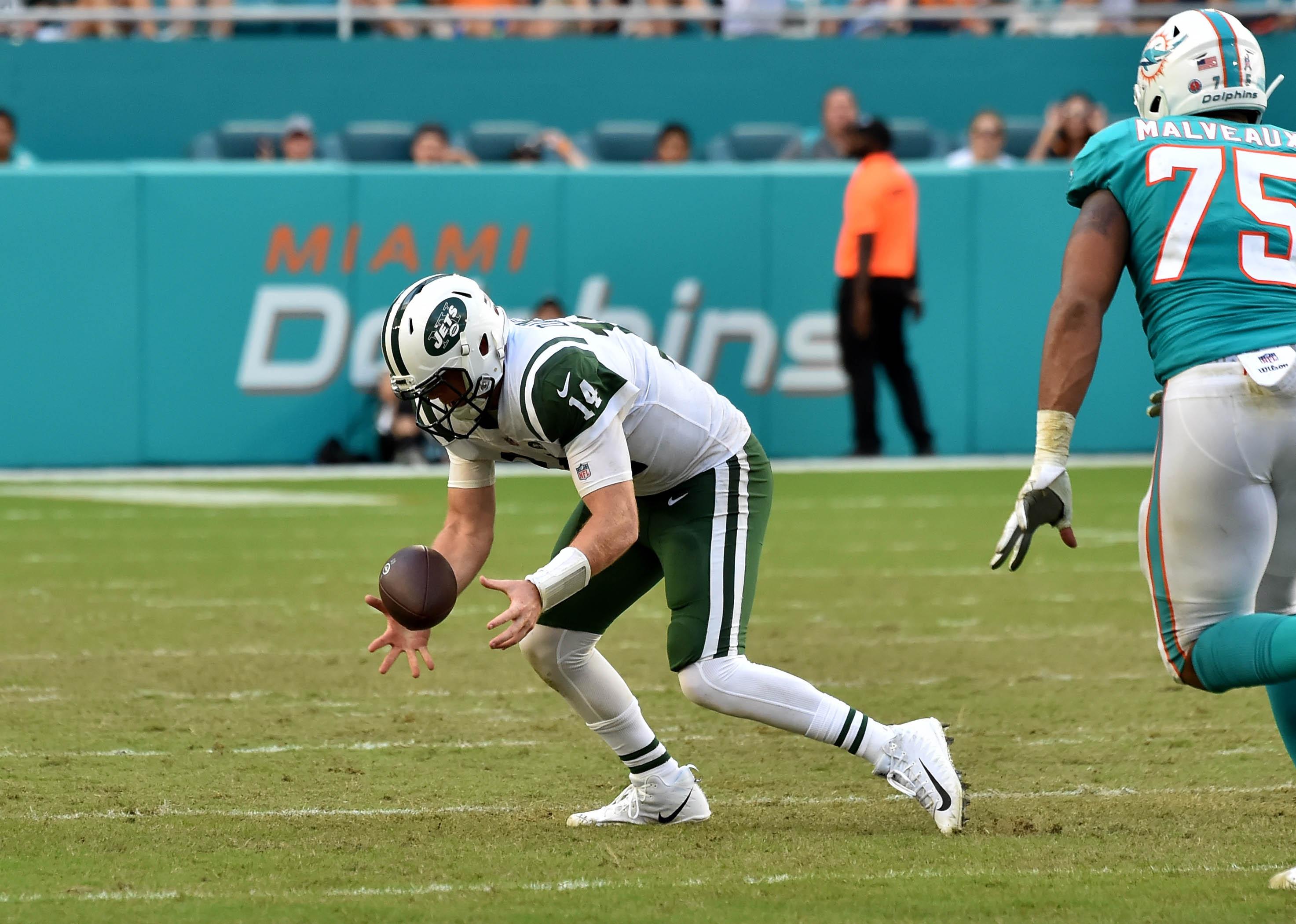 New York Jets quarterback Sam Darnold recovers a high snap as Miami Dolphins defensive end Cameron Malveaux applies pressure during the second half at Hard Rock Stadium.