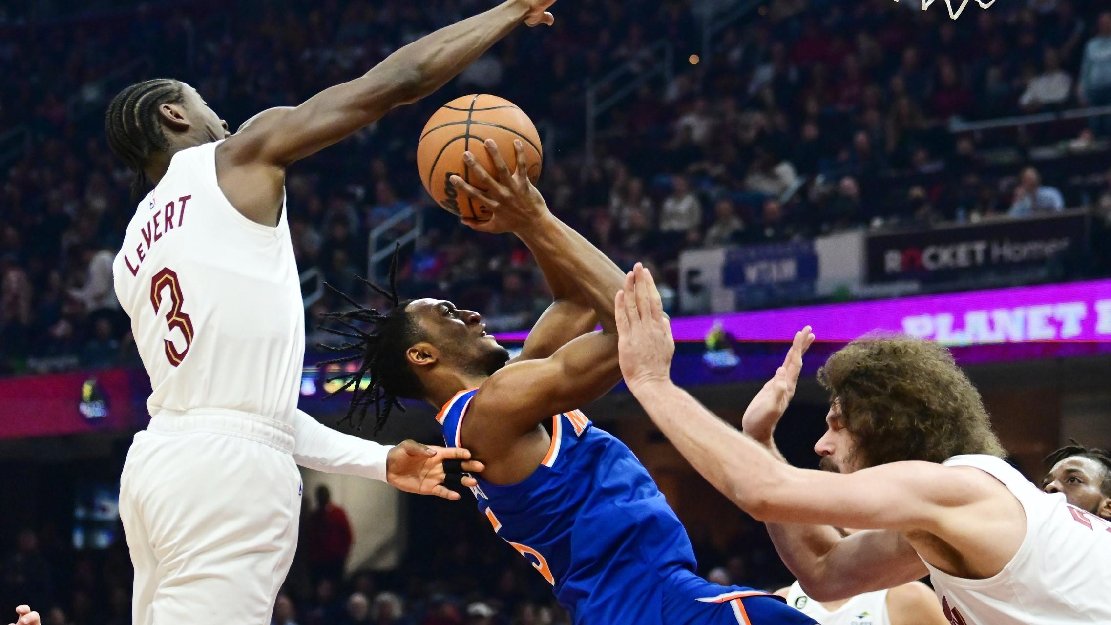 Mar 31, 2023; Cleveland, Ohio, USA; New York Knicks guard Immanuel Quickley (5) drives to the basket between Cleveland Cavaliers guard Caris LeVert (3) and center Robin Lopez (33) during the first half at Rocket Mortgage FieldHouse. / Ken Blaze-USA TODAY Sports