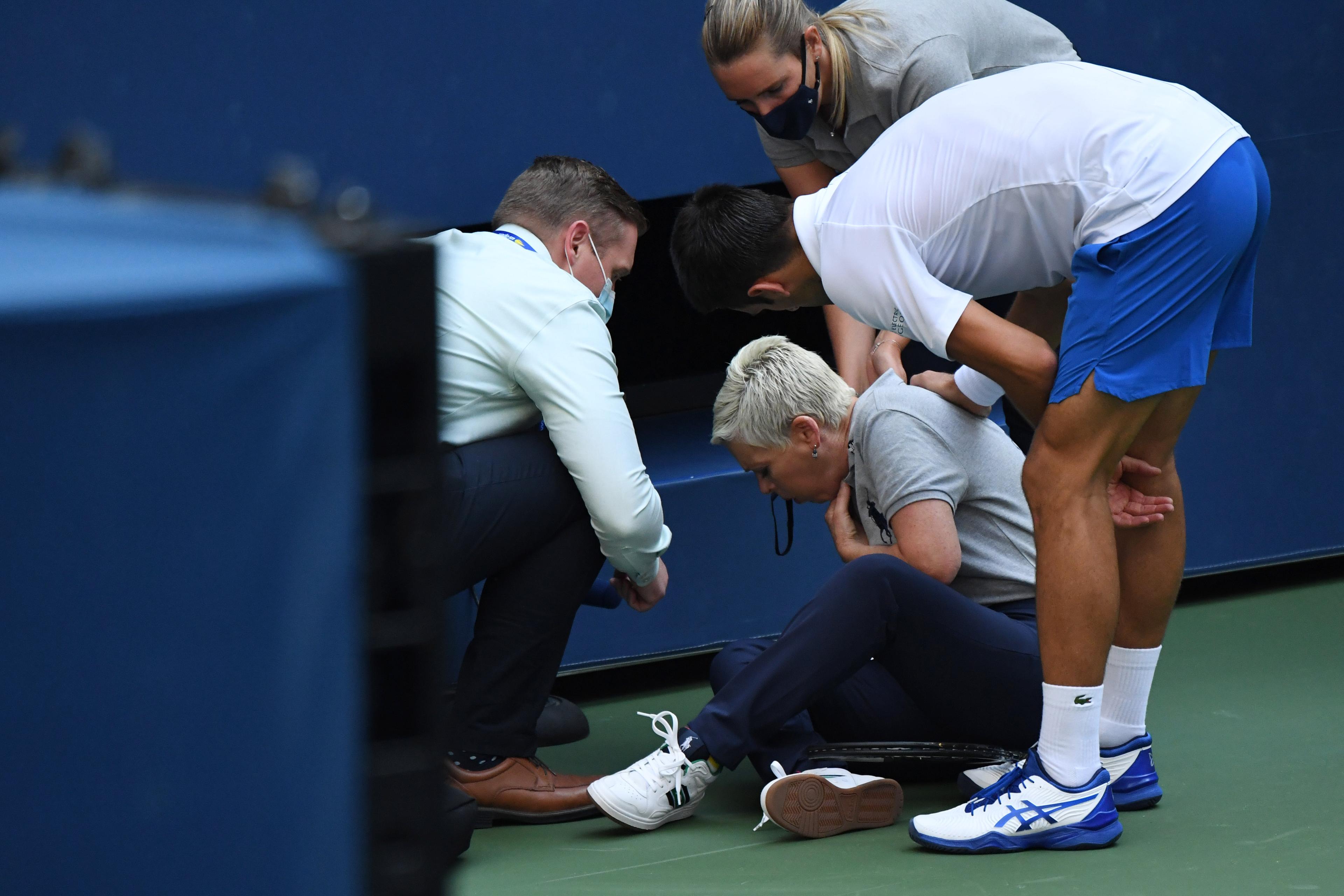 Sep 6, 2020; Flushing Meadows, New York, USA; Novak Djokovic of Serbia and a tournament official tend to a linesperson who was struck with a ball by Djokovic against Pablo Carreno Busta of Spain (not pictured) on day seven of the 2020 U.S. Open tennis tournament at USTA Billie Jean King National Tennis Center. Mandatory Credit: Danielle Parhizkaran-USA TODAY Sports / Danielle Parhizkaran-USA TODAY Sports