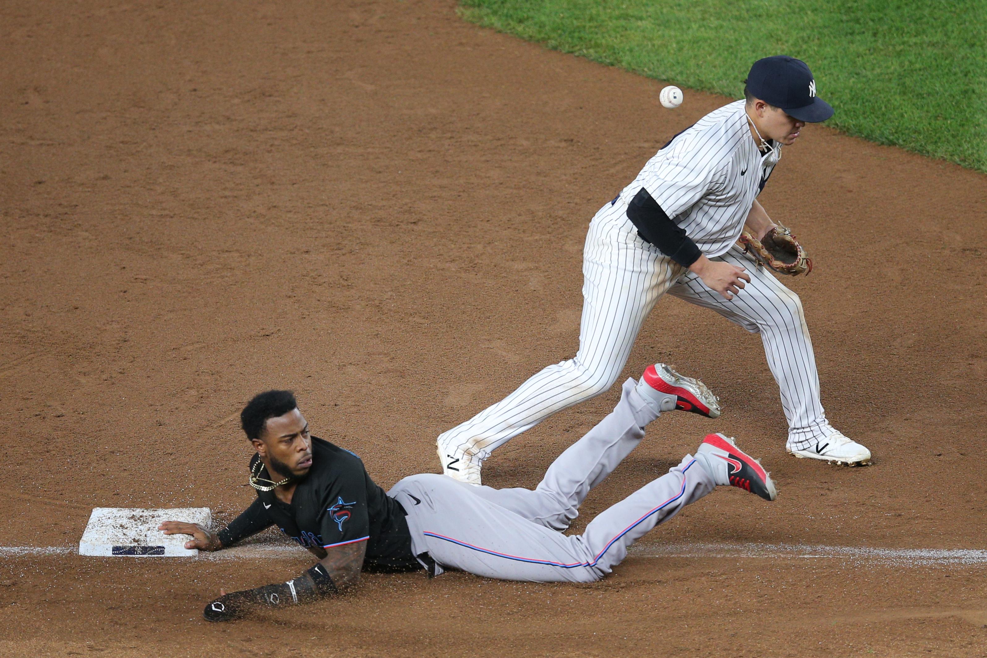 Sep 25, 2020; Bronx, New York, USA; Miami Marlins pinch runner Monte Harrison (4) slides back into third in front of New York Yankees third baseman Gio Urshela (29) after being hit in the back by a throw during a rundown during the tenth inning at Yankee Stadium. Mandatory Credit: Brad Penner-USA TODAY Sports / © Brad Penner-USA TODAY Sports