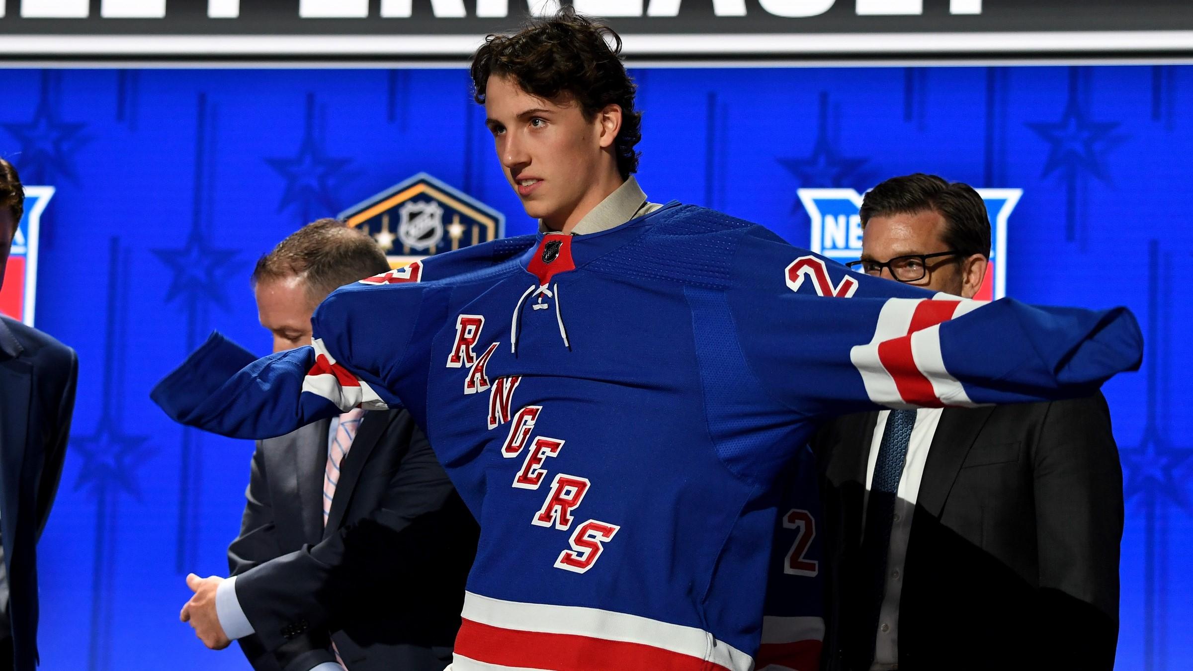 Jun 28, 2023; Nashville, Tennessee, USA; New York Rangers draft pick Gabriel Perreault puts on his sweater after being selected with the twenty third pick in round one of the 2023 NHL Draft at Bridgestone Arena. / Christopher Hanewinckel-USA TODAY Sports