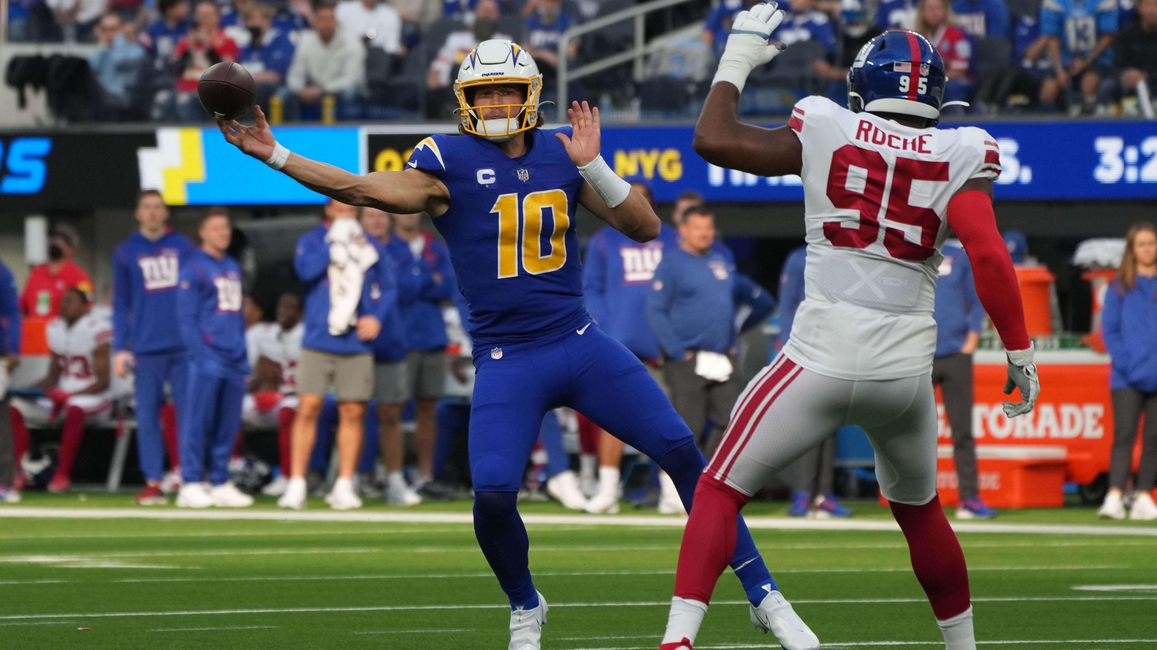 Dec 12, 2021; Inglewood, California, USA; Los Angeles Chargers quarterback Justin Herbert (10) throws the ball under pressure from New York Giants line backer Quincy Roche (95) in the first half at SoFi Stadium. / Kirby Lee-USA TODAY Sports