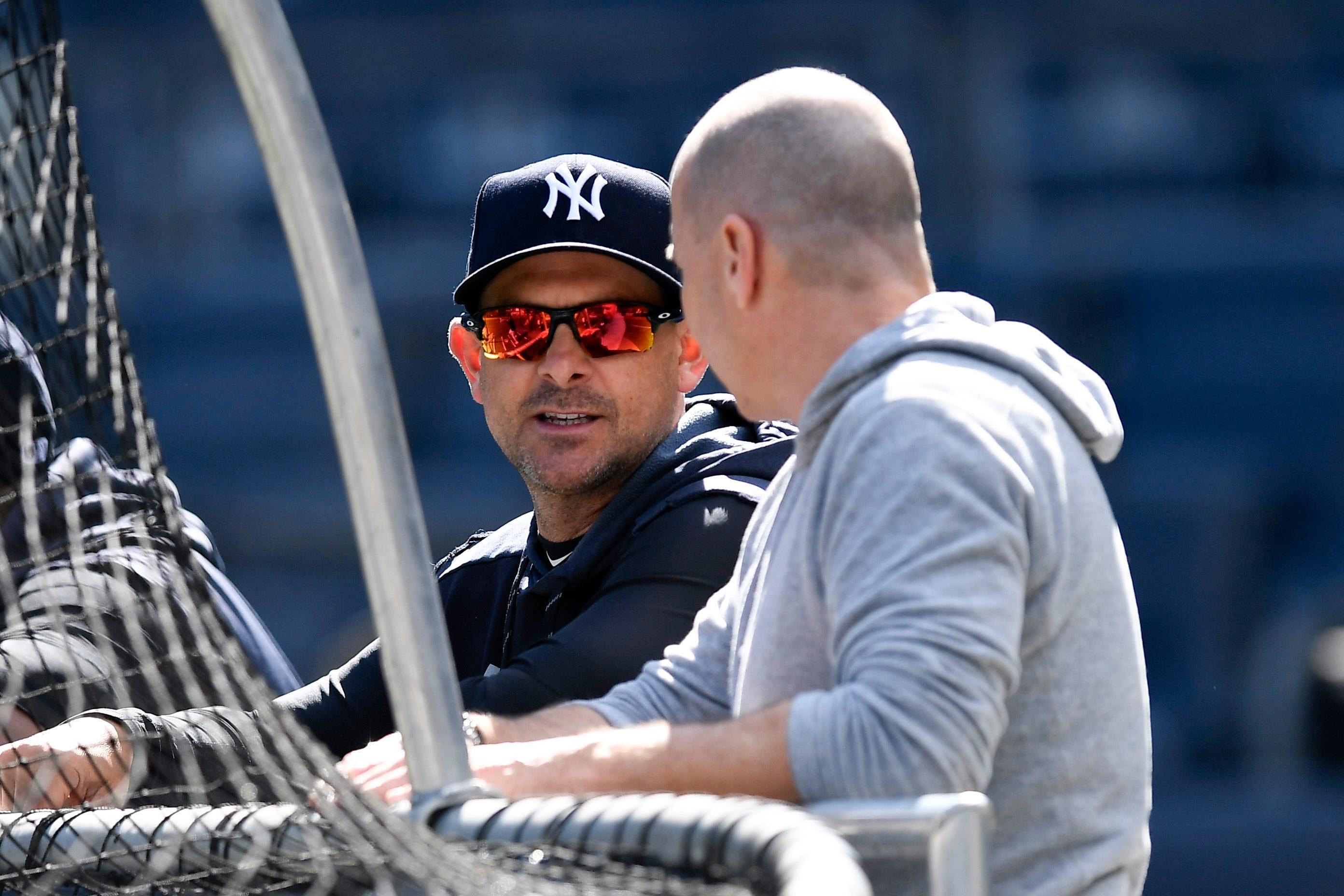 Aaron Boone and Brian Cashman talk at the batting cage / USA Today