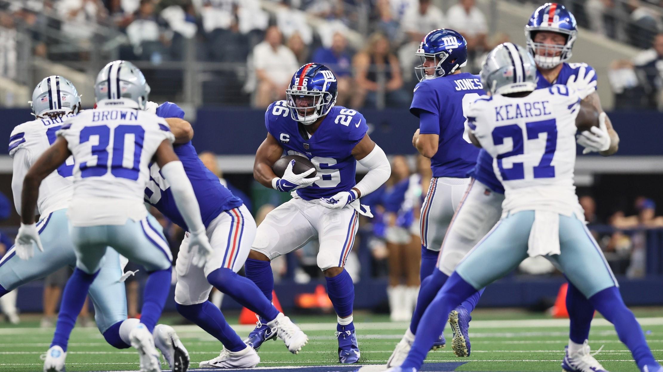 Oct 10, 2021; Arlington, Texas, USA; New York Giants running back Saquon Barkley (26) carries the ball in the first quarter as Dallas Cowboys cornerback Anthony Brown (30) defends at AT&T Stadium. / Matthew Emmons-USA TODAY Sports