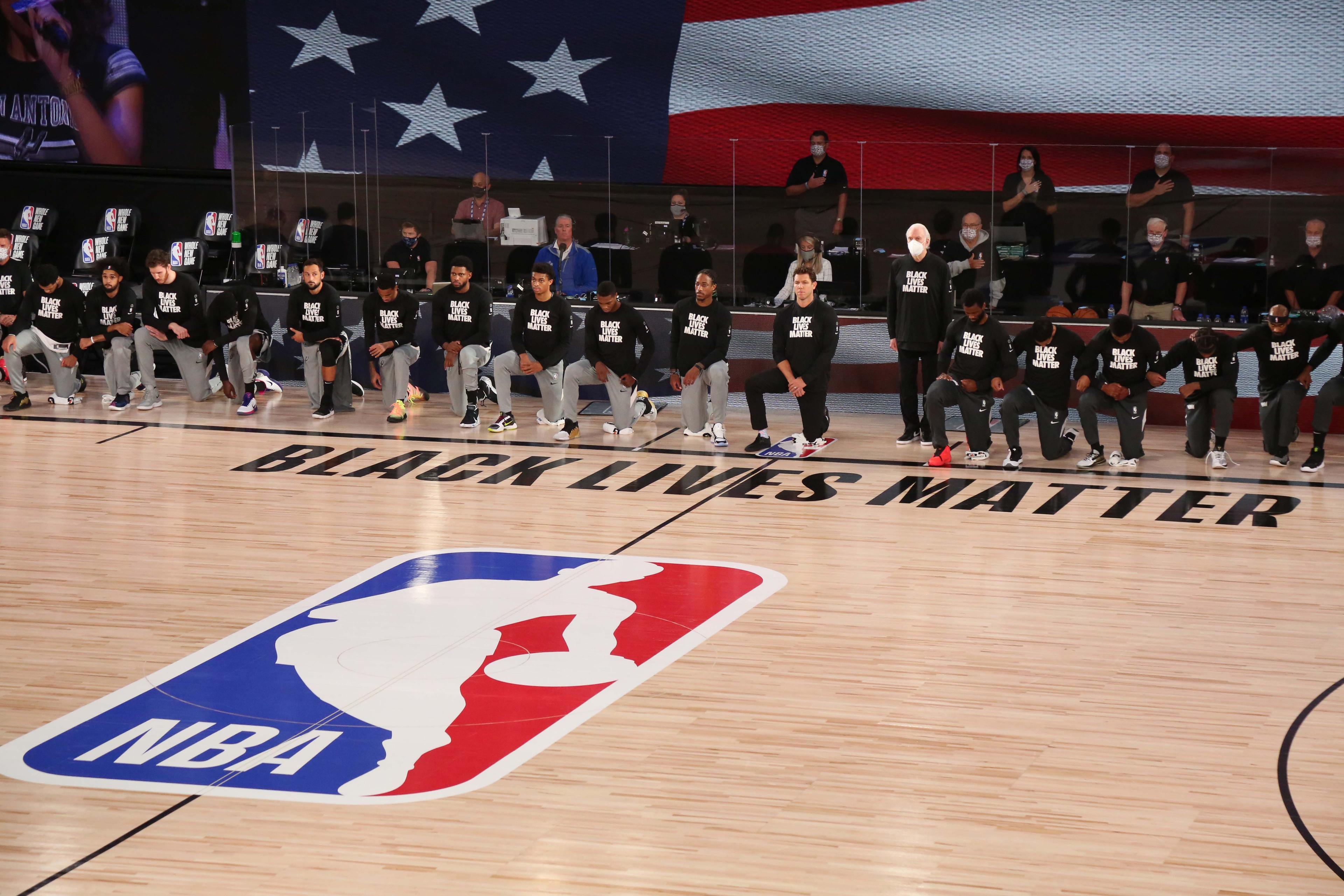 Jul 31, 2020; Lake Buena Vista, Florida, USA; San Antonio Spurs head coach Gregg Popovich stands as other players and staff on the Spurs and the Sacramento Kings kneel around a Black Lives Matters logo on the court before a NBA basketball game at the Visa Athletic Center in the ESPN Wide World of Sports Complex. / Kim Klement-USA TODAY Sports