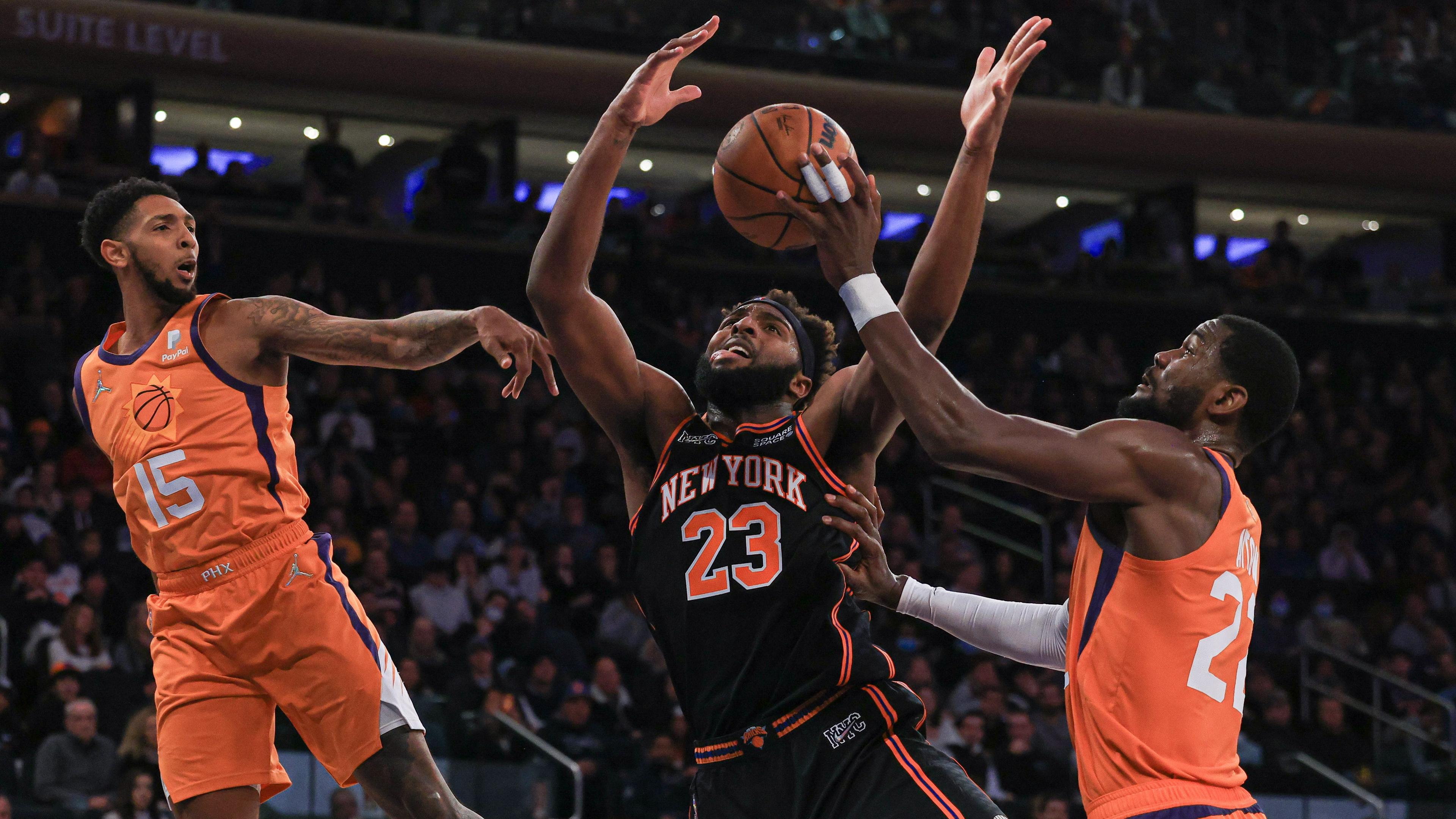 Nov 26, 2021; New York, New York, USA; New York Knicks center Mitchell Robinson (23) battles for a rebound against Phoenix Suns guard Cameron Payne (15) and center Deandre Ayton (22) during the first half at Madison Square Garden. / Vincent Carchietta-USA TODAY Sports