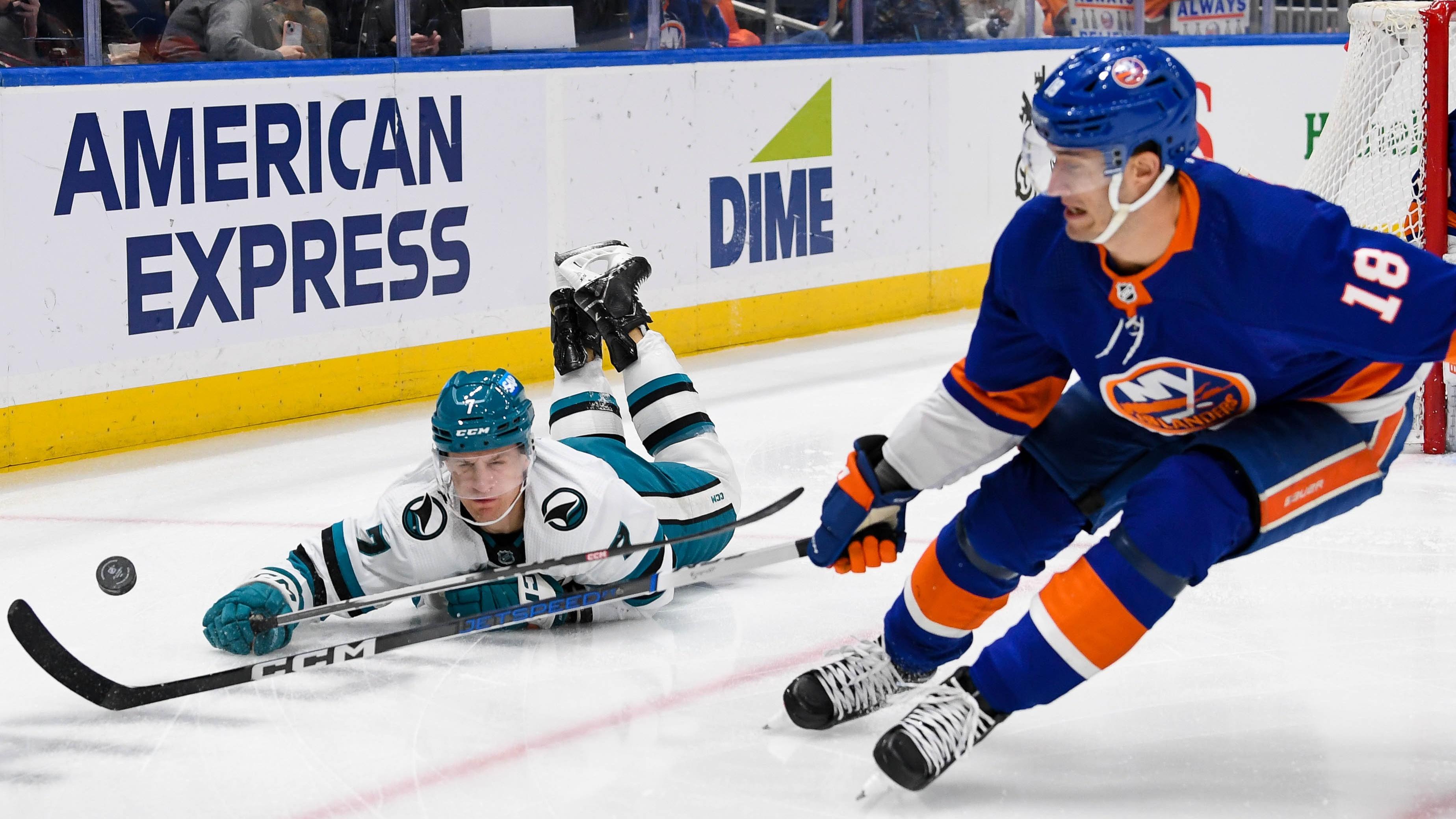 San Jose Sharks center Nico Sturm (7) dives for a loose puck defended by New York Islanders left wing Pierre Engvall (18) during the first period at UBS Arena / Dennis Schneidler - USA TODAY Sports