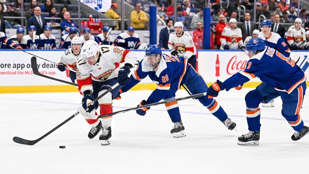 Florida Panthers center Evan Rodrigues (17) skates with the puck defended by New York Islanders defenseman Alexander Romanov (28) and New York Islanders defenseman Noah Dobson (8) during the first period at UBS Arena / Dennis Schneidler-USA TODAY Sports