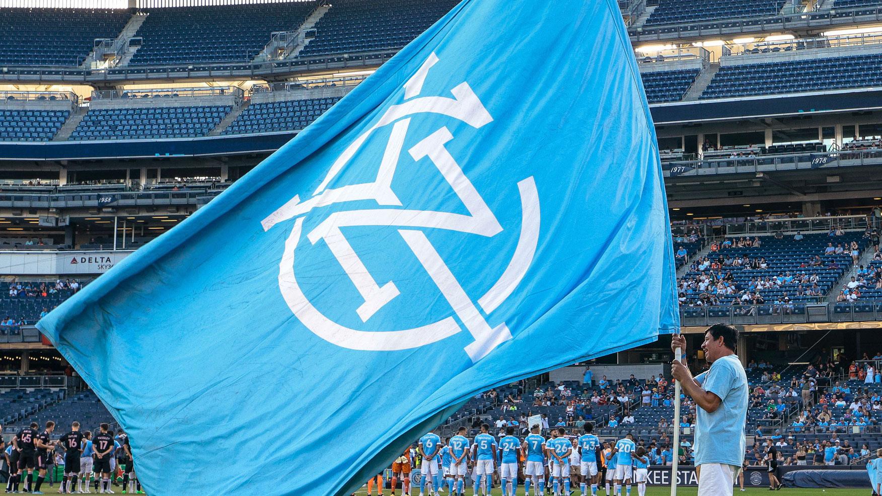 Jul 23, 2022; New York, New York, USA; A fan holds a NYCFC flag on the pitch before a match between New York City FC and Inter Miami CF at Yankee Stadium. / Vincent Carchietta-USA TODAY Sports