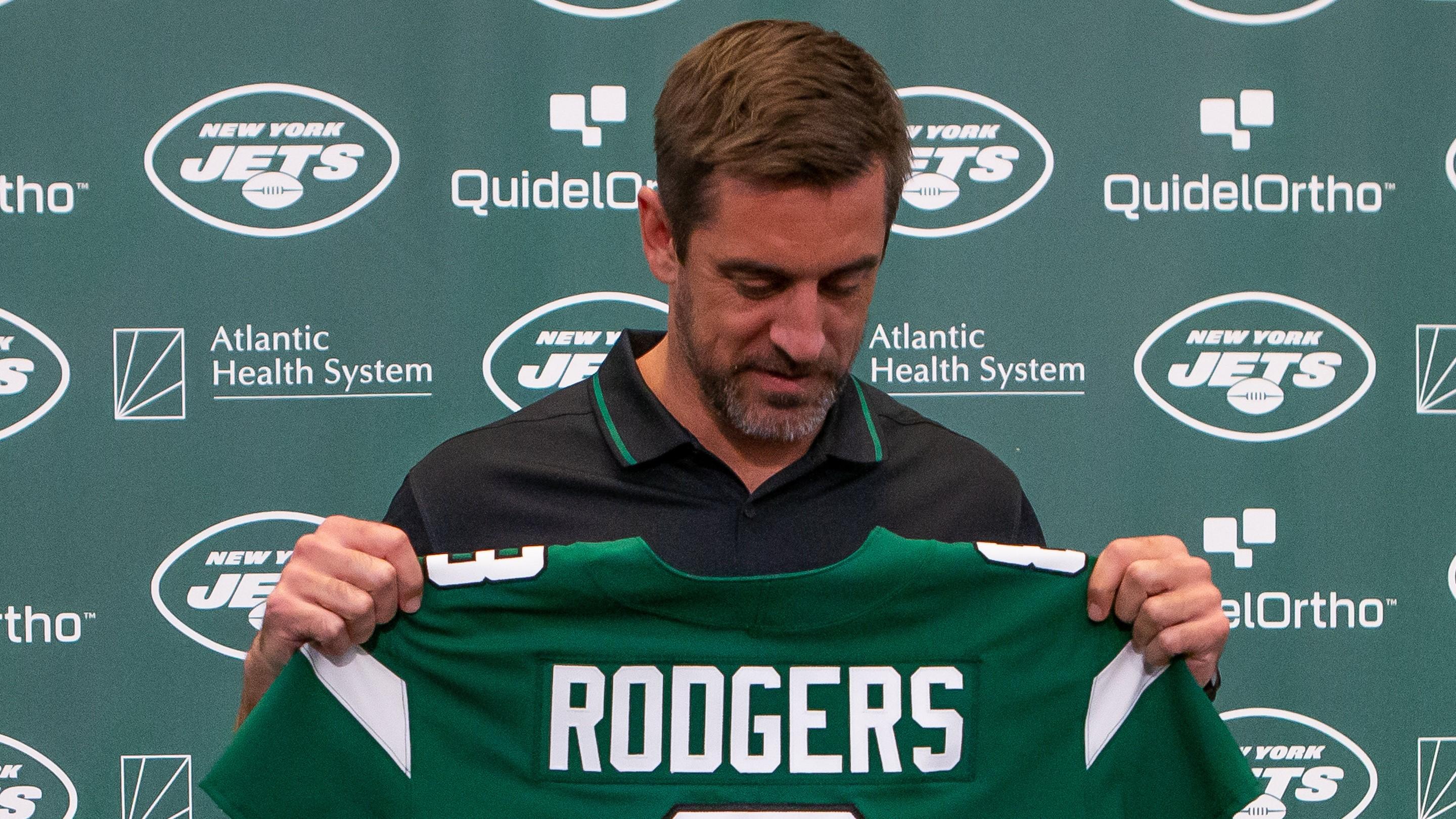 Aaron Rodgers looks down at his No. 8 Jets jersey during his introductory news conference. / Tom Horak-USA TODAY Sports