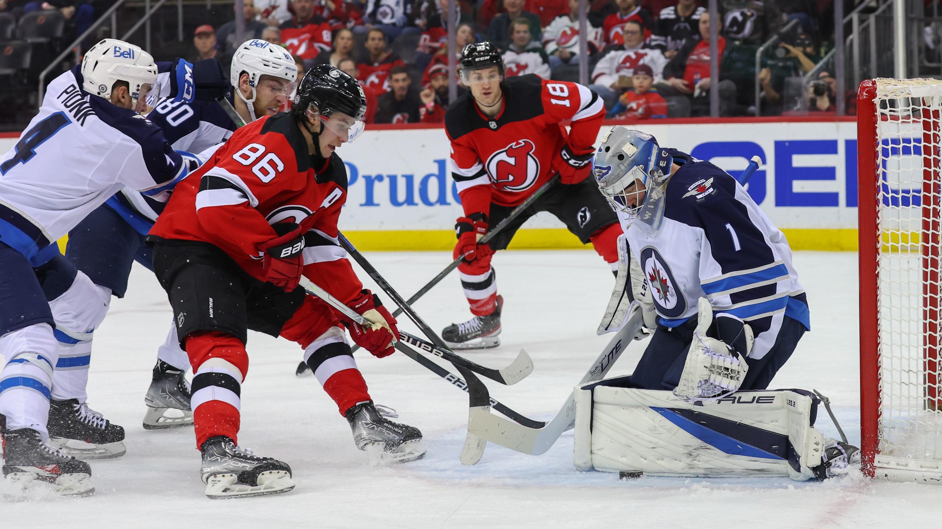 Mar 10, 2022; Newark, New Jersey, USA; Winnipeg Jets goaltender Eric Comrie (1) makes a save on New Jersey Devils center Jack Hughes (86) during the second period at Prudential Center. Mandatory Credit: Ed Mulholland-USA TODAY Sports / Ed Mulholland-USA TODAY Sports