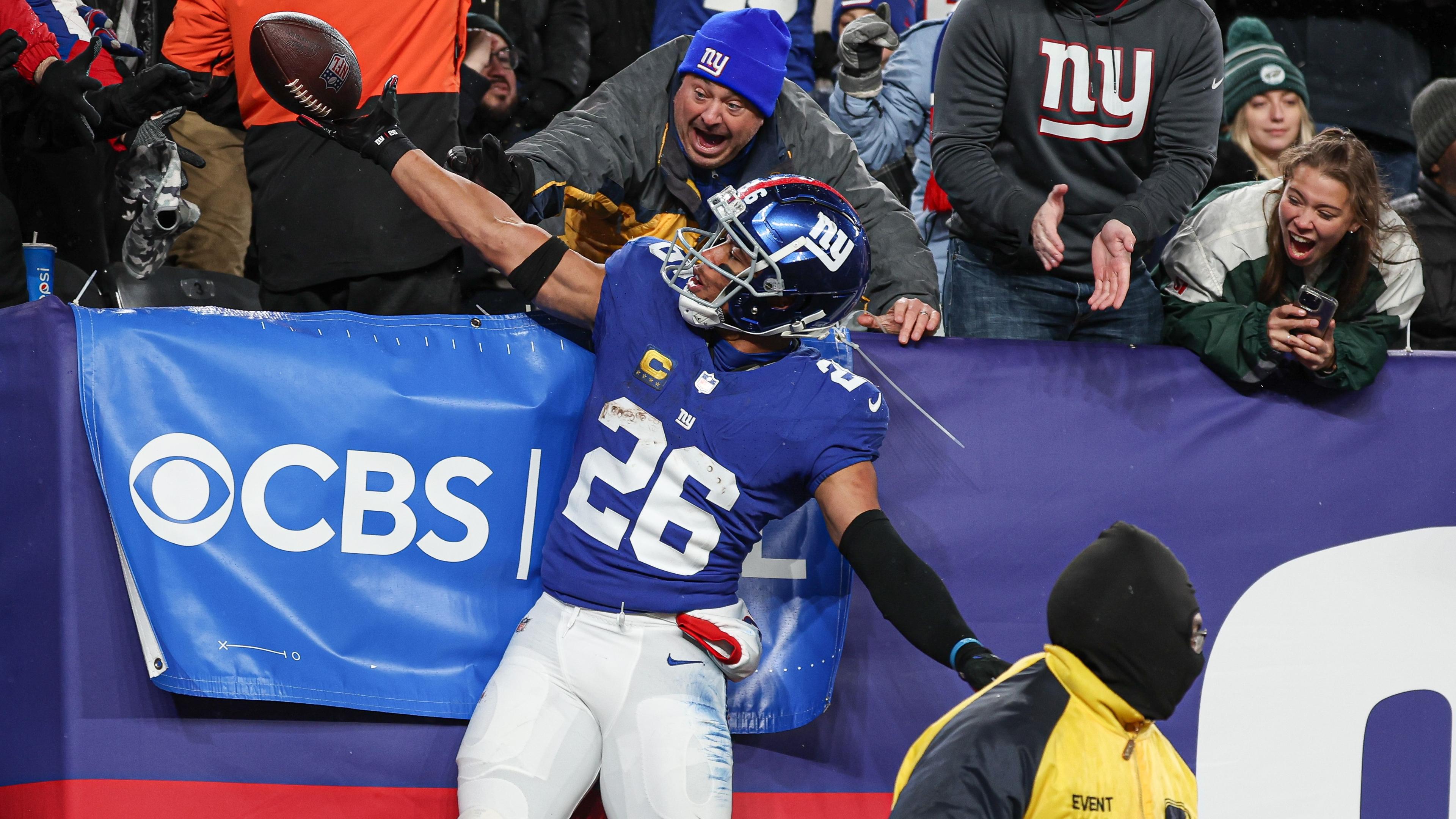Jan 7, 2024; East Rutherford, New Jersey, USA; New York Giants running back Saquon Barkley (26) gives the game ball to a young fan after scoring his second touchdown of the game during the first half against the Philadelphia Eagles at MetLife Stadium. Mandatory Credit: Vincent Carchietta-USA TODAY Sports / © Vincent Carchietta-USA TODAY Sports