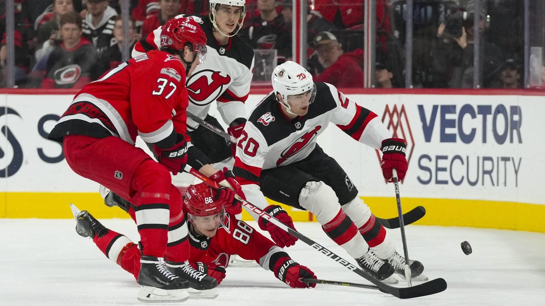 Dec 20, 2022; Raleigh, North Carolina, USA; Carolina Hurricanes center Martin Necas (88) and right wing Andrei Svechnikov (37) battle for the puck against New Jersey Devils center Michael McLeod (20) during the second period at PNC Arena. / James Guillory-USA TODAY Sports